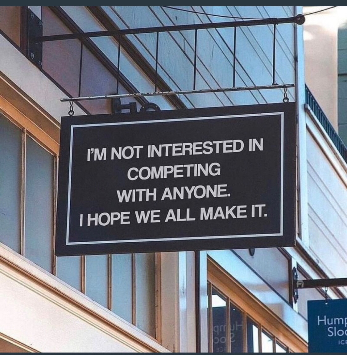 A sign reads “I’m not interested in competing with anyone. I hope we all make it.”