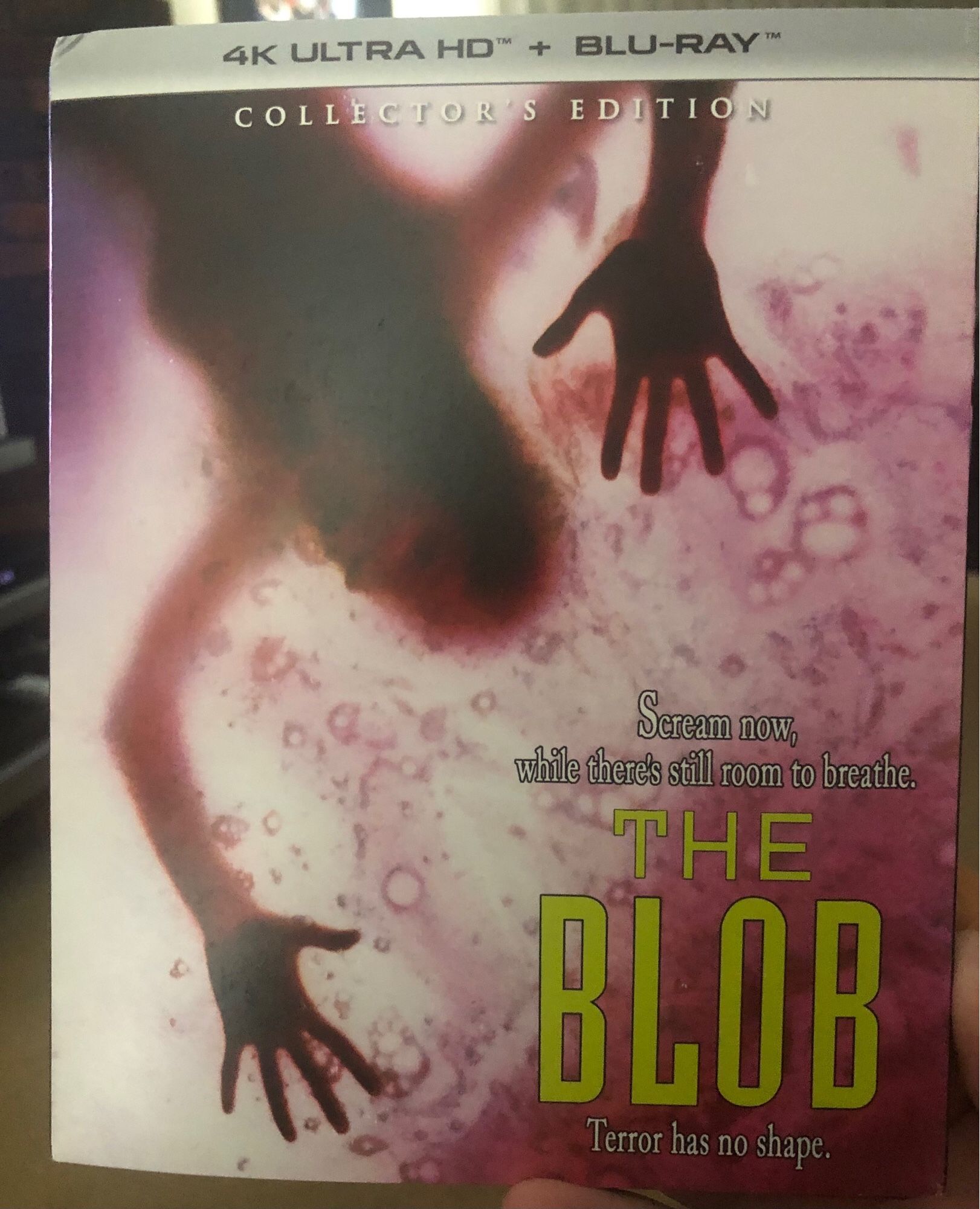 The 4K Ultra HD/Blu-Ray edition of the 1988 remake of THE BLOB, depicting a woman being devoured by the eponymous pink mass, the text on the cover reading “Scream now, while there’s still room to breathe,” and “Terror has no shape.”