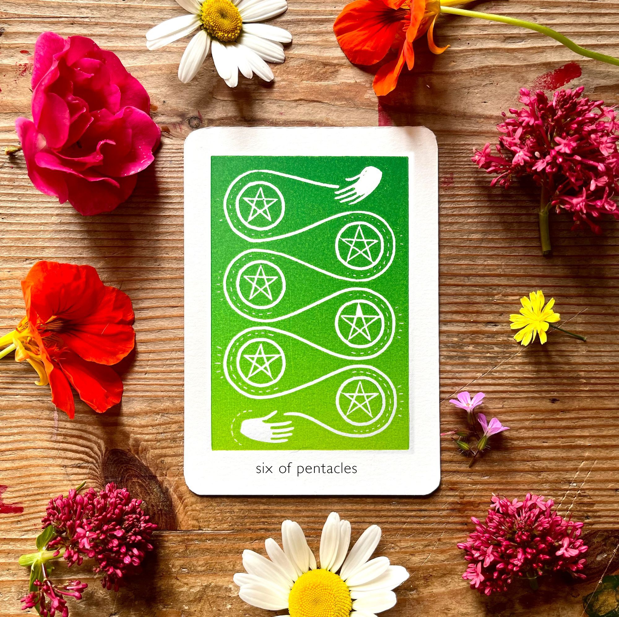 a linoprinted tarot card of the 6 of pentacles. there's a gradient of mid green at the top to spring green at the bottom. there's a hand at the top in a gesture of giving, and a hand at the bottom in a gesture of receiving. from the hand at the top is a looping line which makes its way around 6 pentacles, which sparkle with energy.