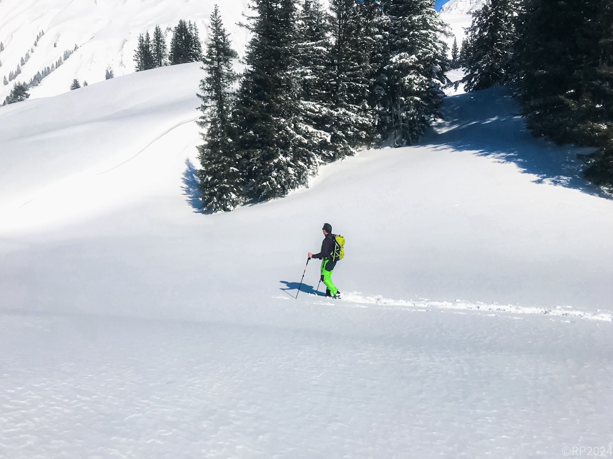 Ein Schneeschuhwanderer zieht seine Spur durch eine tiefverschneite Berglandschaft.