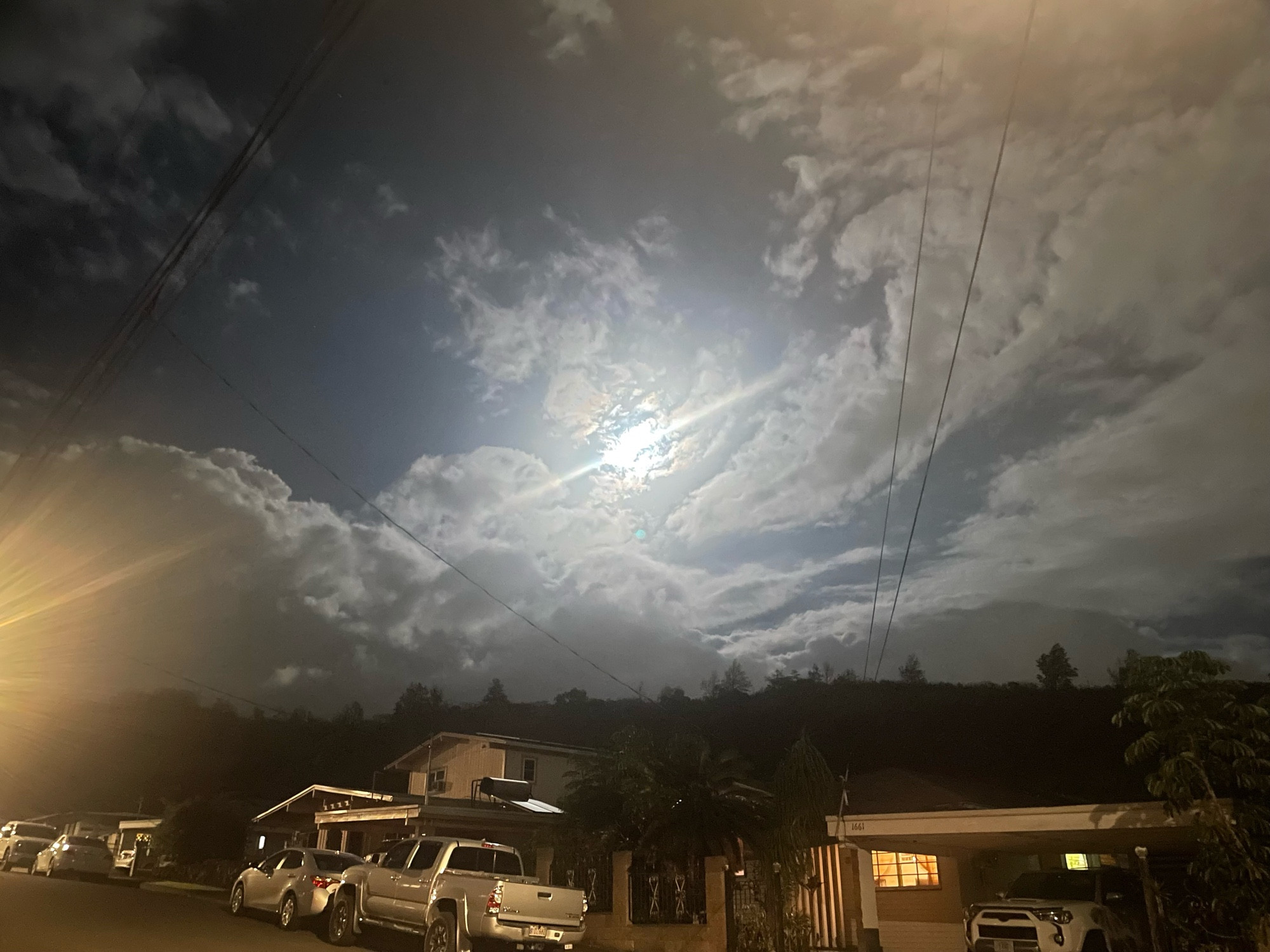 The moon behind wispy, curled clouds that frame it asymmetrically