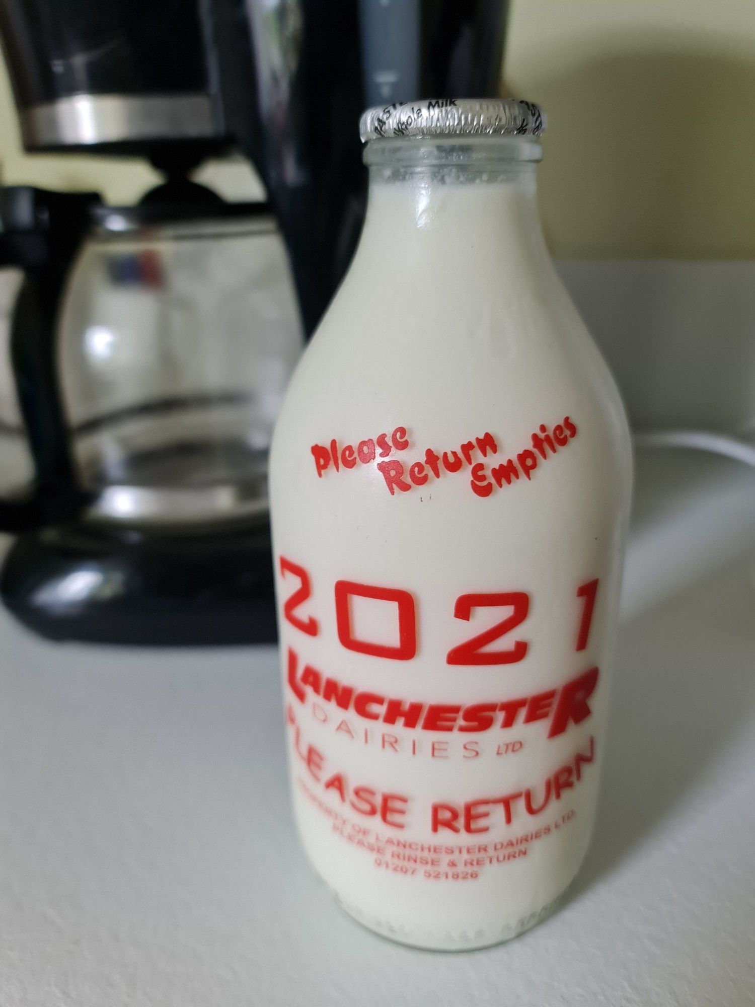 A glass bottle of fresh milk printed with the name of the dairy and the year the bottle was produced, namely 2021.