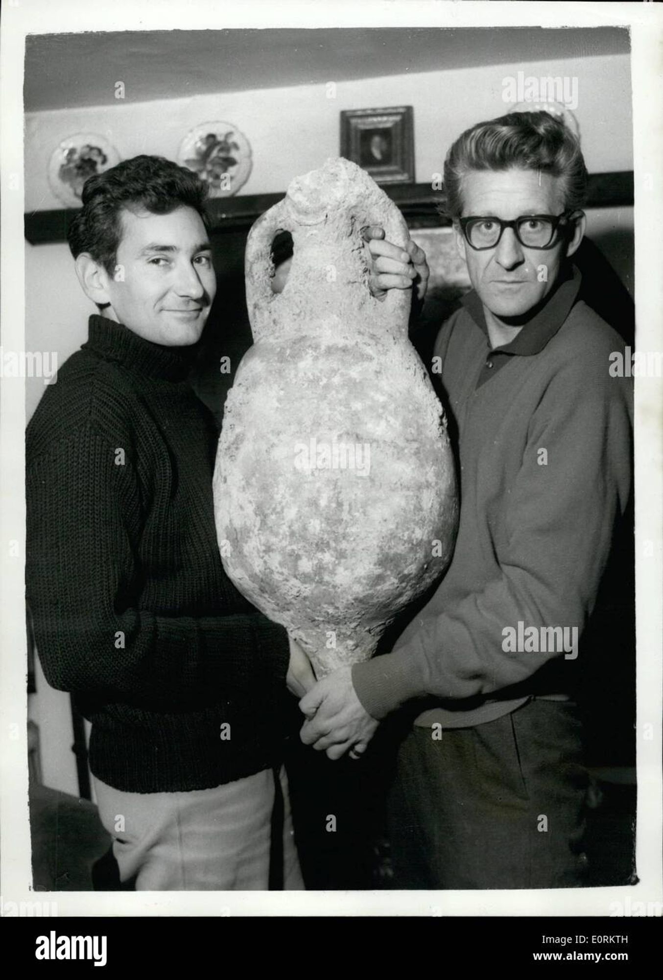 An image nicked off Alamy of Jon Pertwee and another man posing holding an ancient amphora in some sort of cottage.