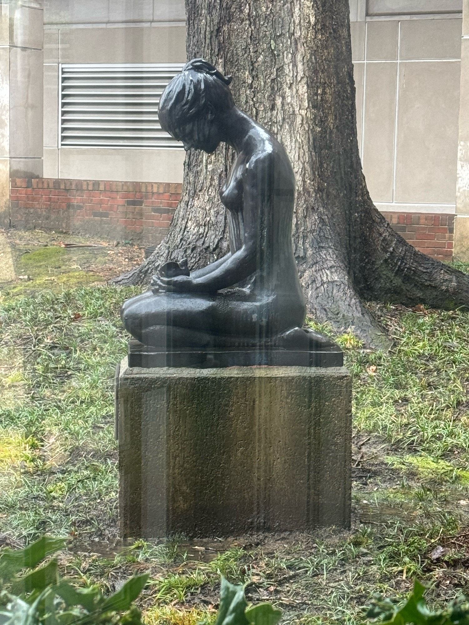 Image of a statue of a young woman, sitting on her knees and holding a bird with cupped hands. She’s looking down at the bird.