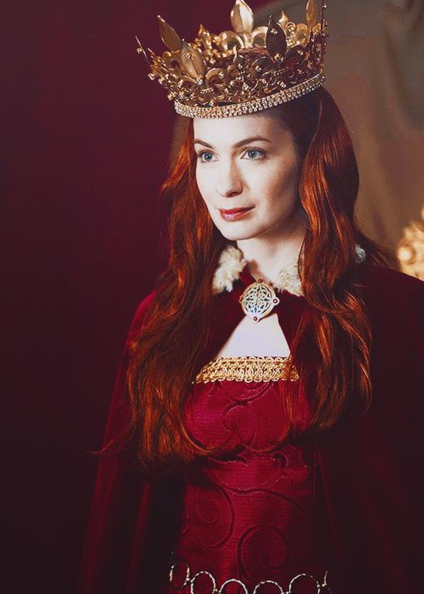 Charlie Bradbury played by Felicia Day in a red royal outfit complete with crown and Celtic clasp.