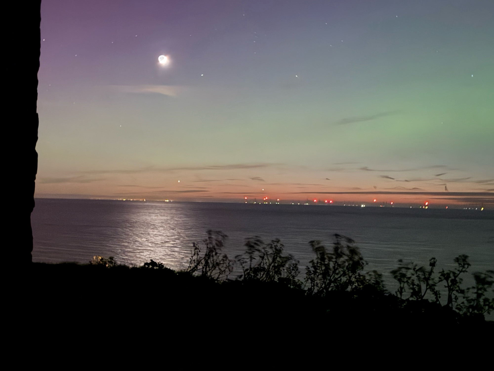 The view from Reculver towers facing slightly north west. You can see the crescent moon in the top left hand side, the reflection of the moon on the Thames estuary just below. The lights of Essex are visible ok the horizon, while a slight green glow from the aurora can be seen to the right of the picture in the middle of the frame.