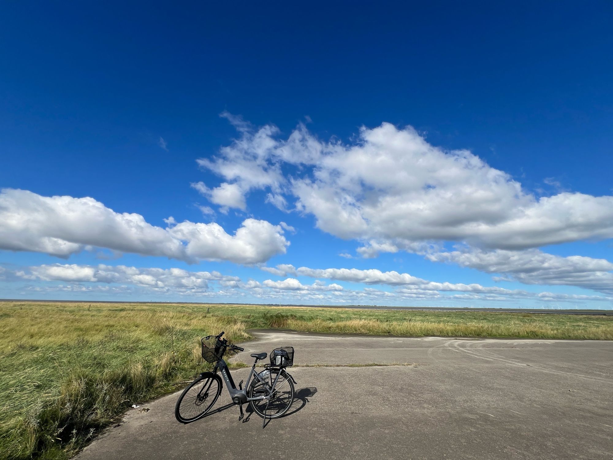 Ein Fahrrad steht auf der Hallig Helmsand unter einem blauen Himmel und weißen Wolken.