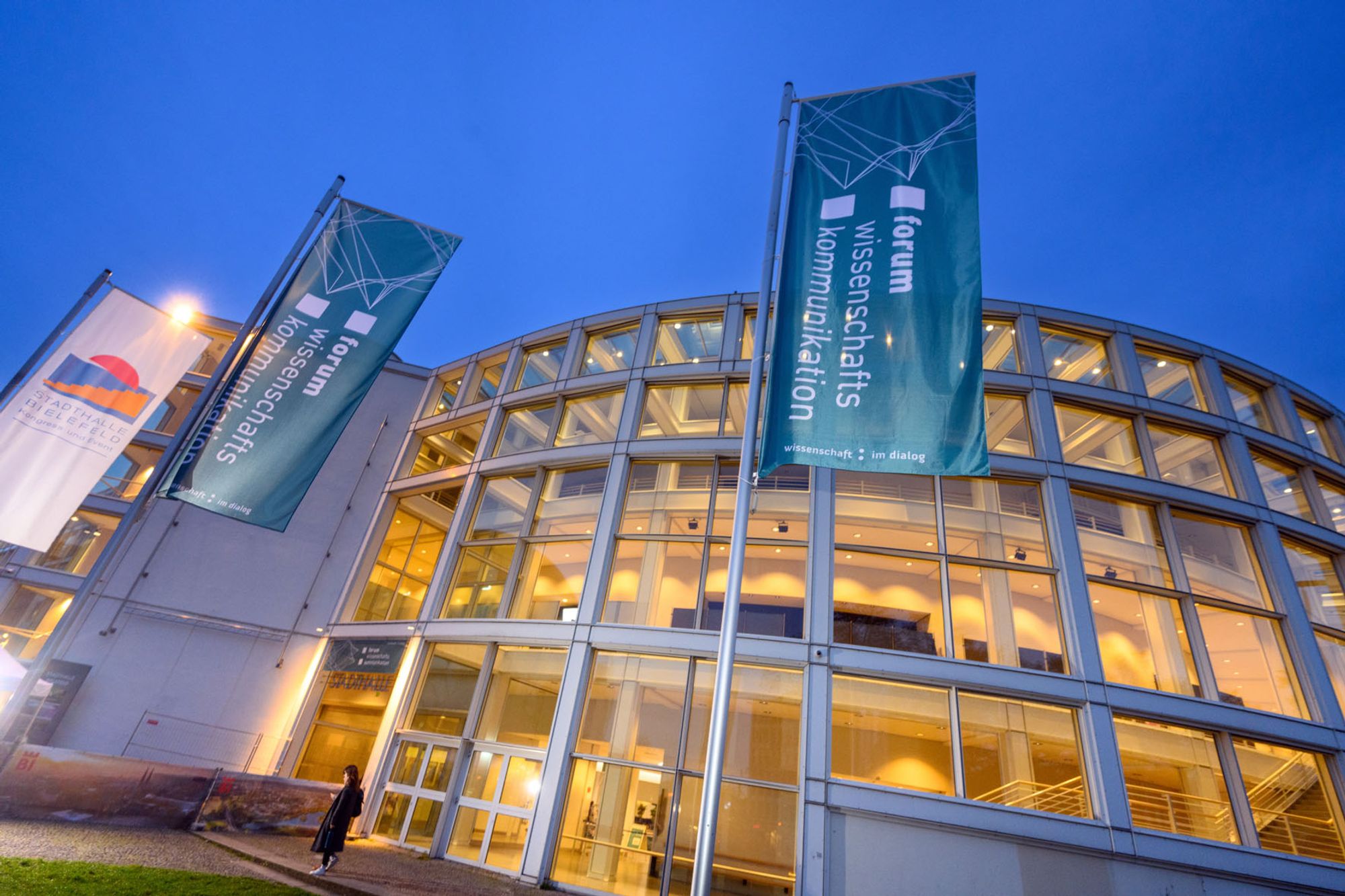 Zwei Banner Forum Wissenschaftskommunikation vor erleuchteter Stadthalle Bielefeld am Abend