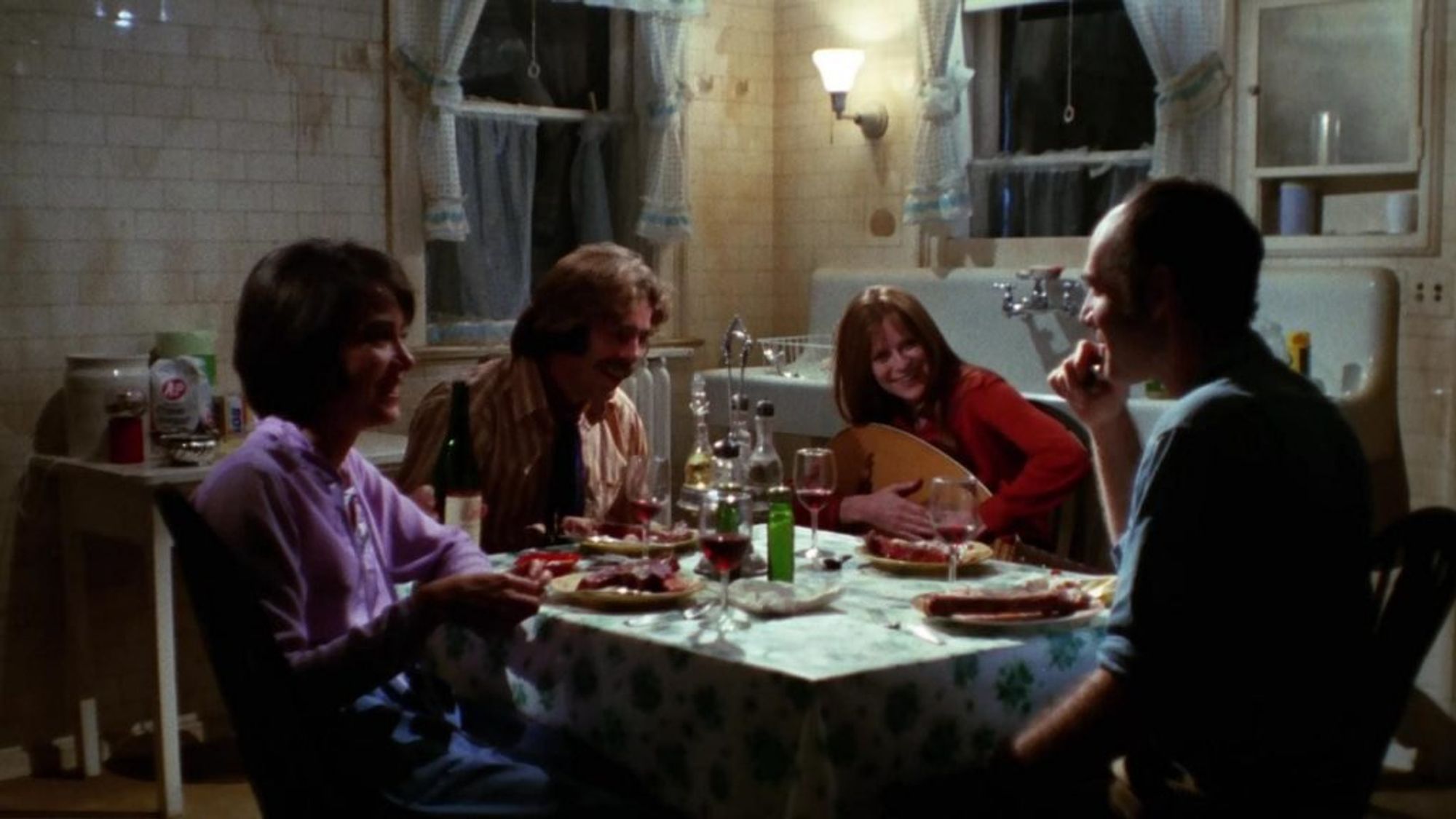 Four early 1970s weirdos sitting around a table playing a lute and eating raw meat as one does.