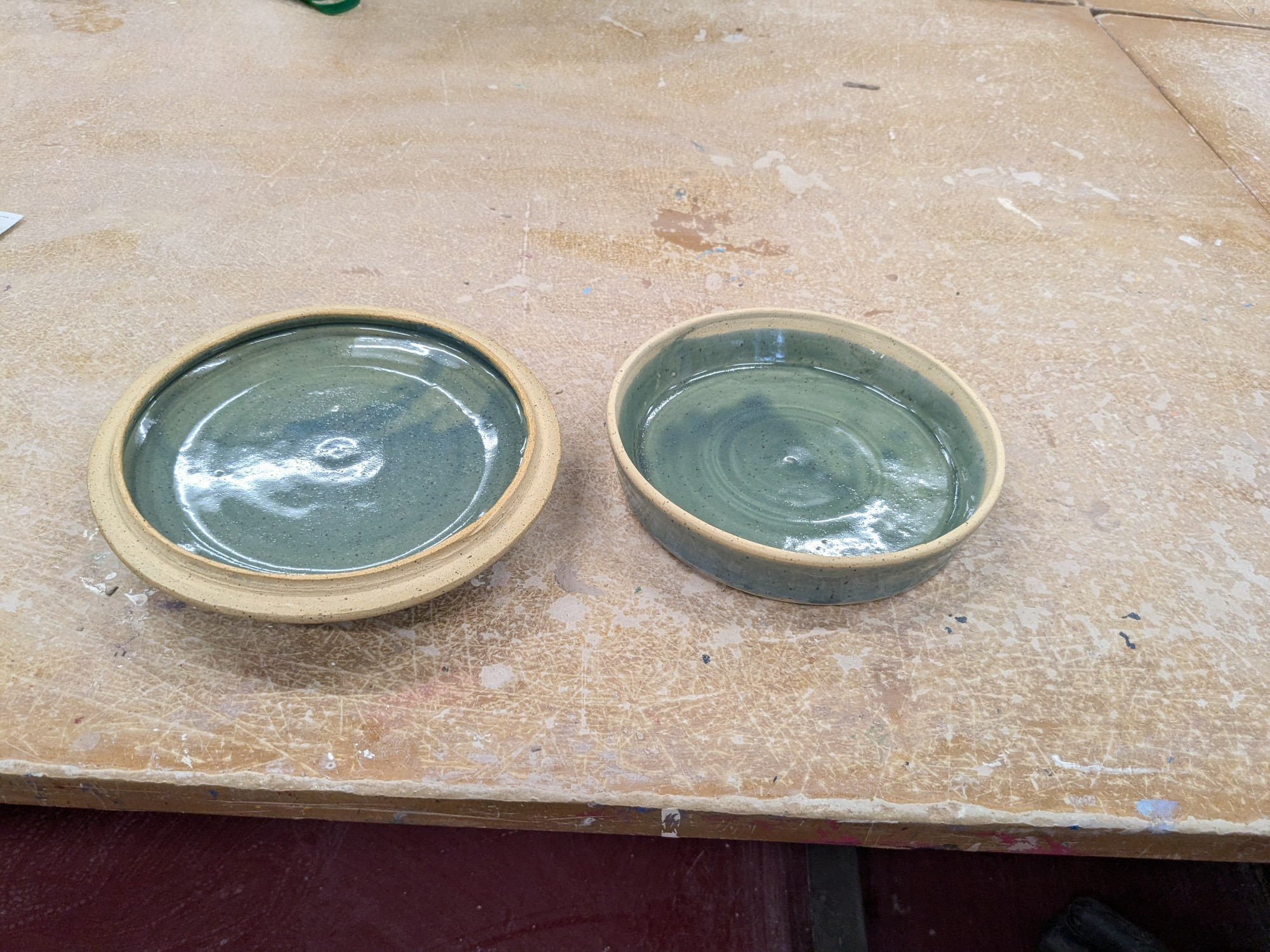 The lid and base of a lidded casserole, made from buff colored clay with a translucent pale blue glaze.