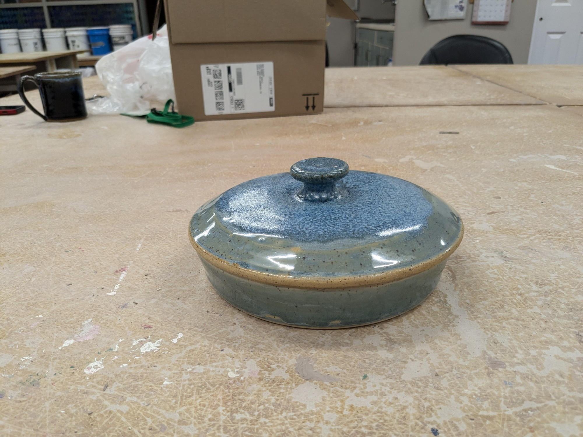 The lidded casserole with its lid in place, its handle and blue glazed top visible.