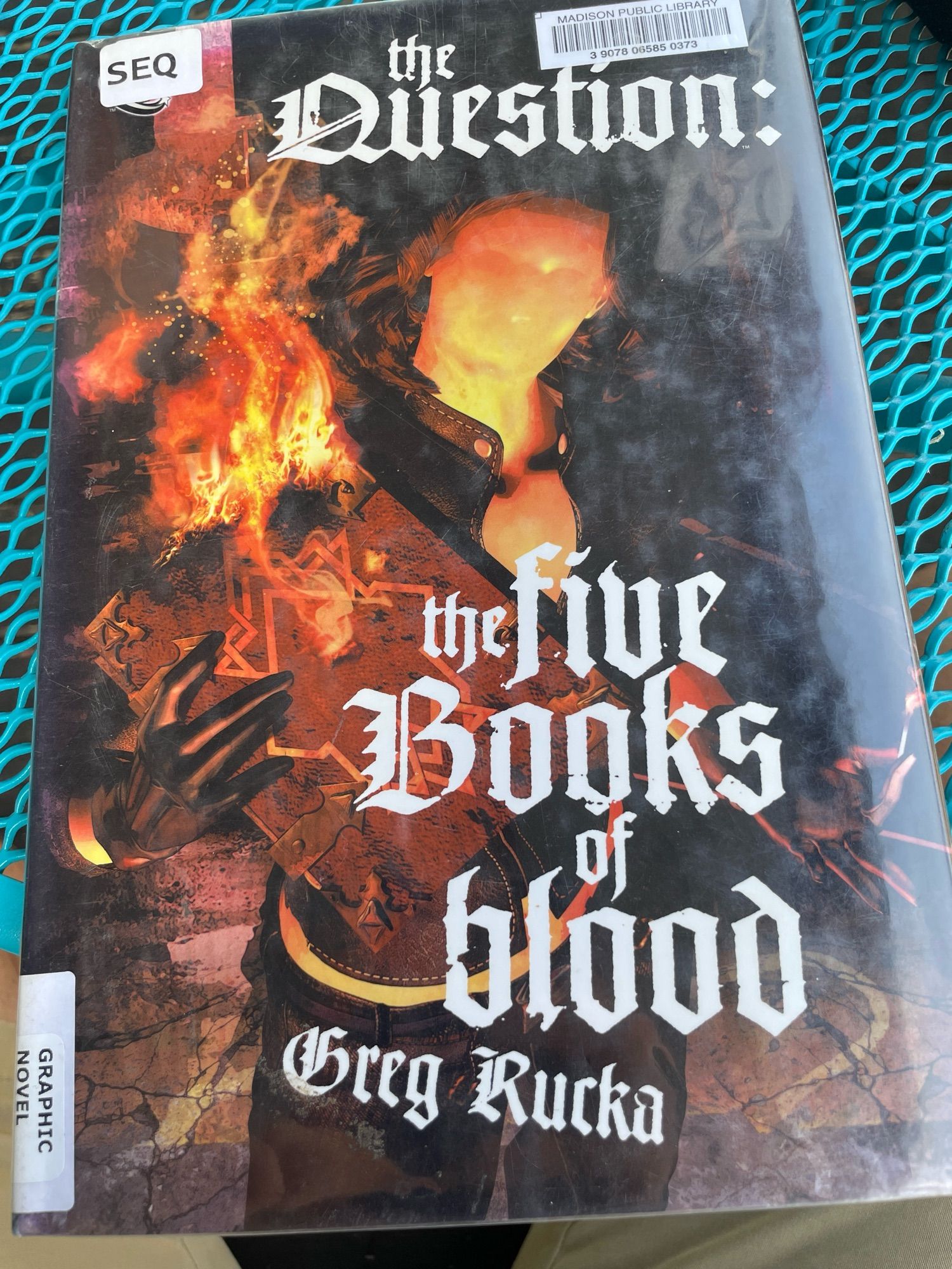 Graphic novel — “The Question: The Five Books of Blood” by Greg Rucka — cover features a faceless hero holding a burning book.