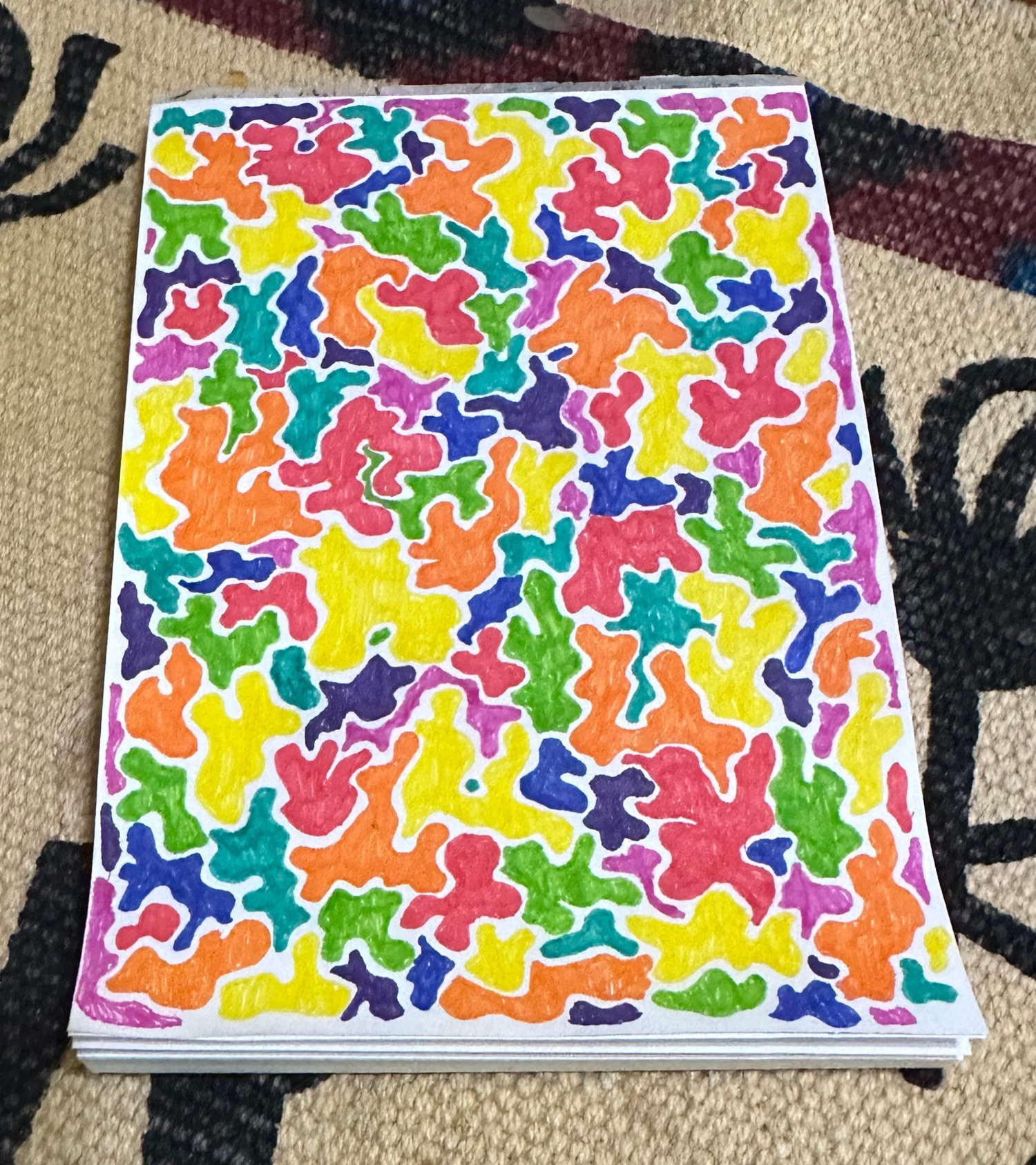 A pad of paper with the top sheet filled with varied blobs of color, filling in all the space.