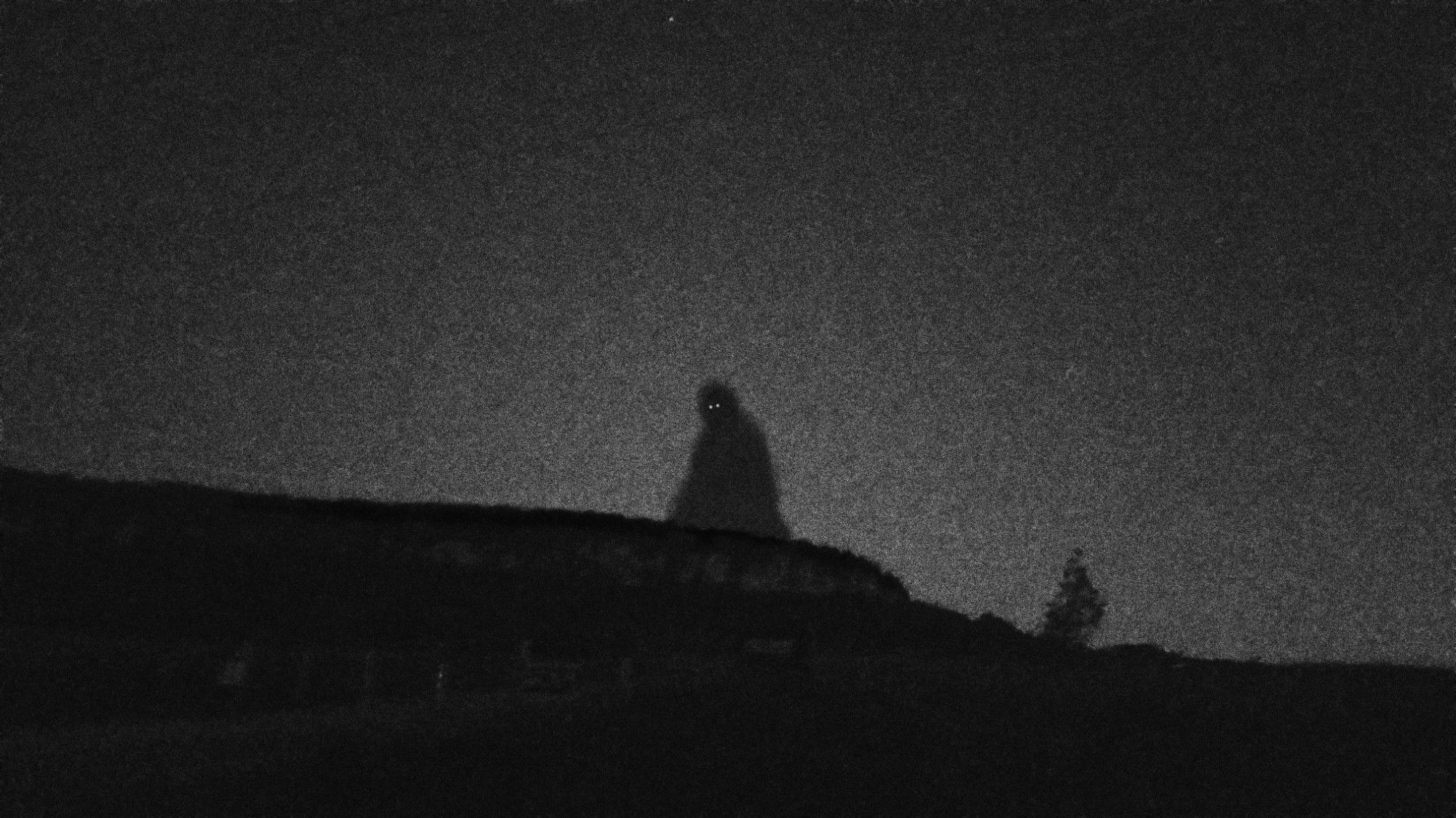 A large shadow figure taller than the mountains in the distance stares at you