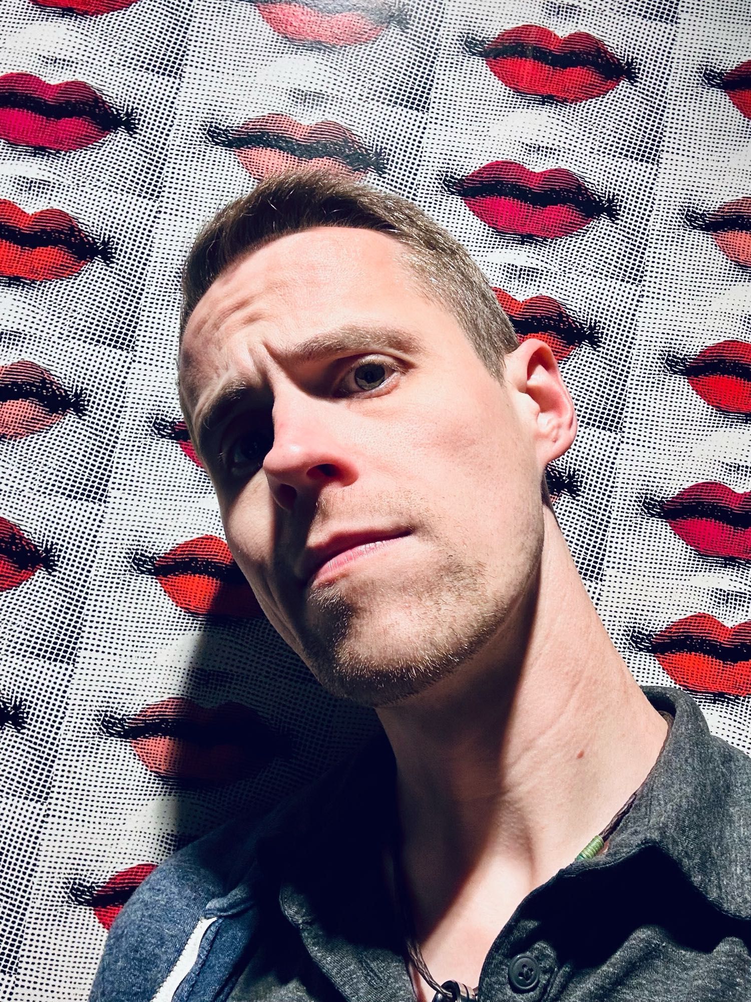 Curtis posing in front of wallpaper with lips on it 👄