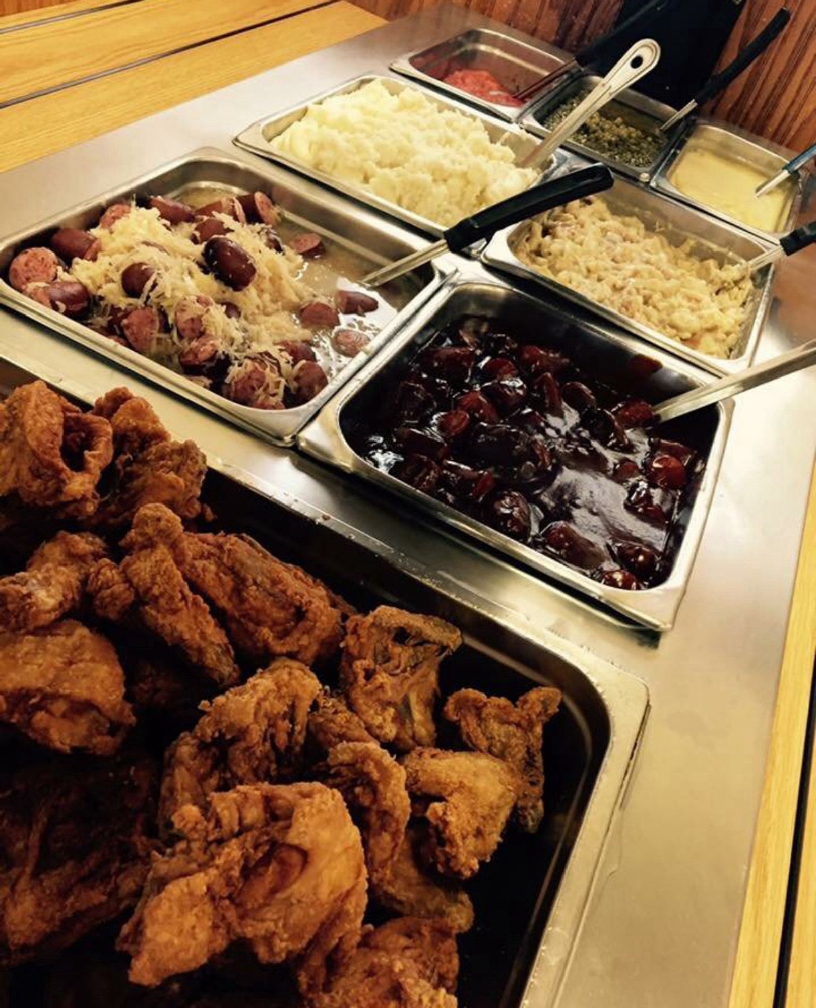 Sunday buffet of fried chicken, sauerkraut and sausage, several unknown food items, mashed potatoes, carrot medallions, country gravy