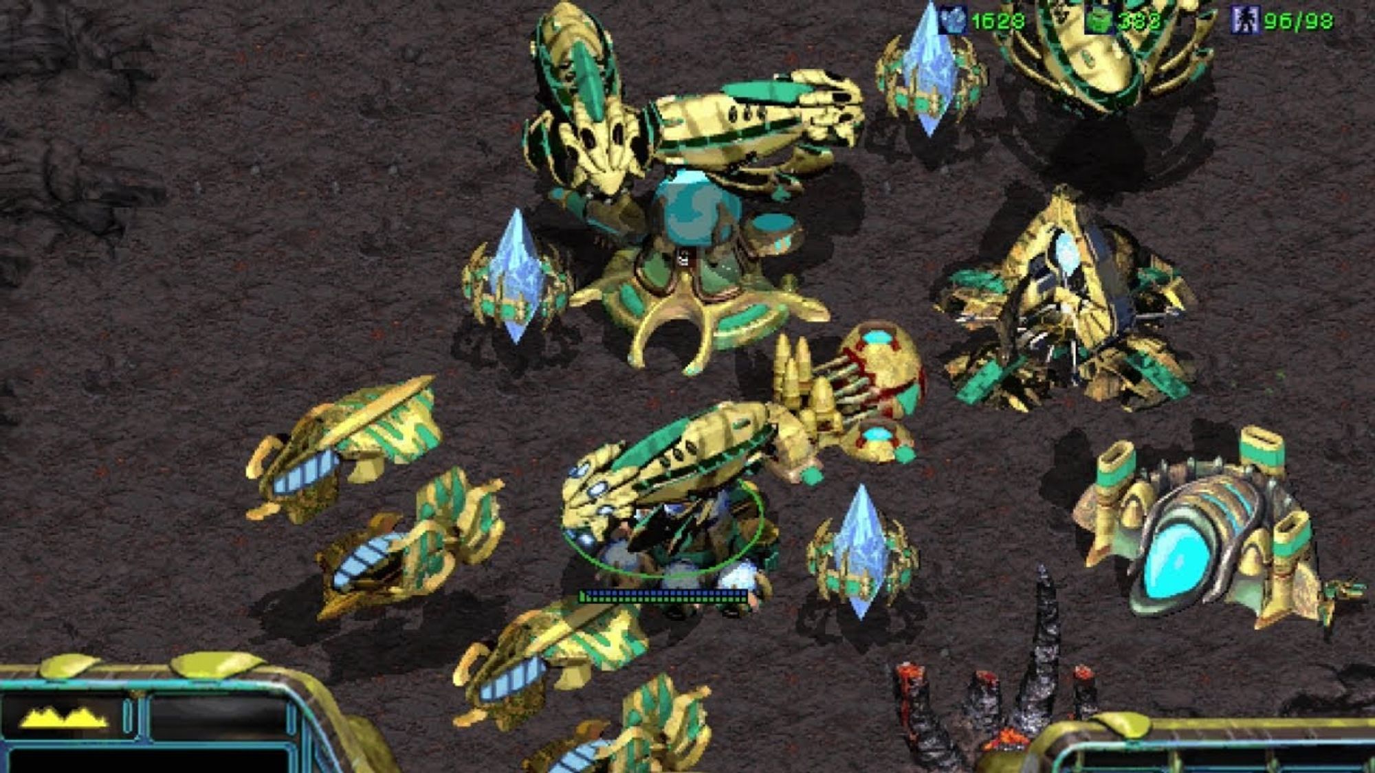 A gameplay screenshot of StarCraft show casing the Protoss, the humanoid alien race. There are Carriers, which are massive ships that deploy little robots that shoot down the enemy with laser fire, alongside many buildings. The buildings have a lot of curves and are rounded.