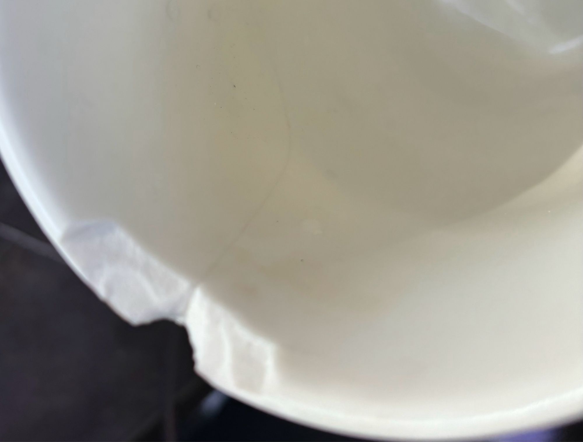 Inside of a white stoneware mug showing a crack and a massive chip broken off