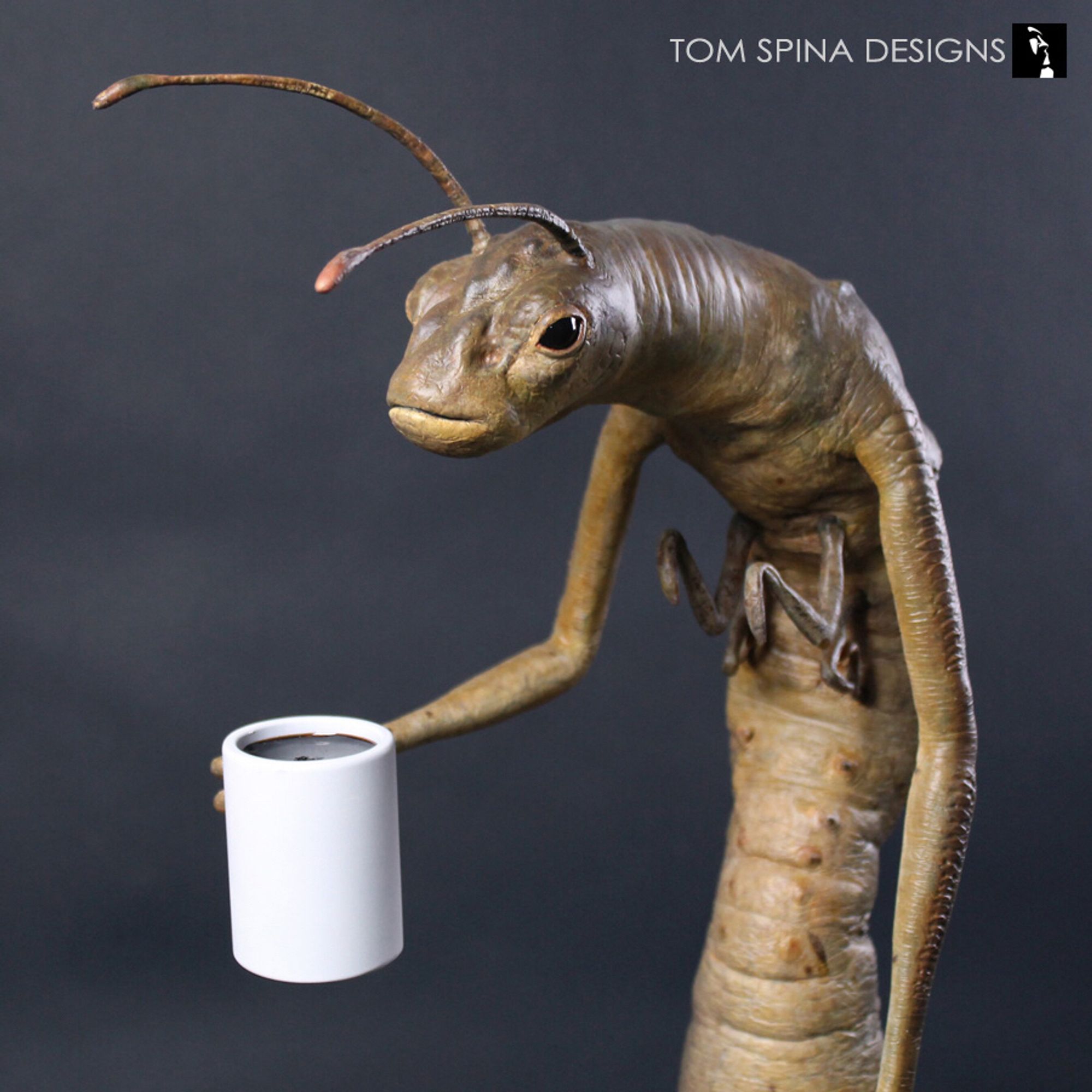 Men in black alien worm holding a cup of coffee