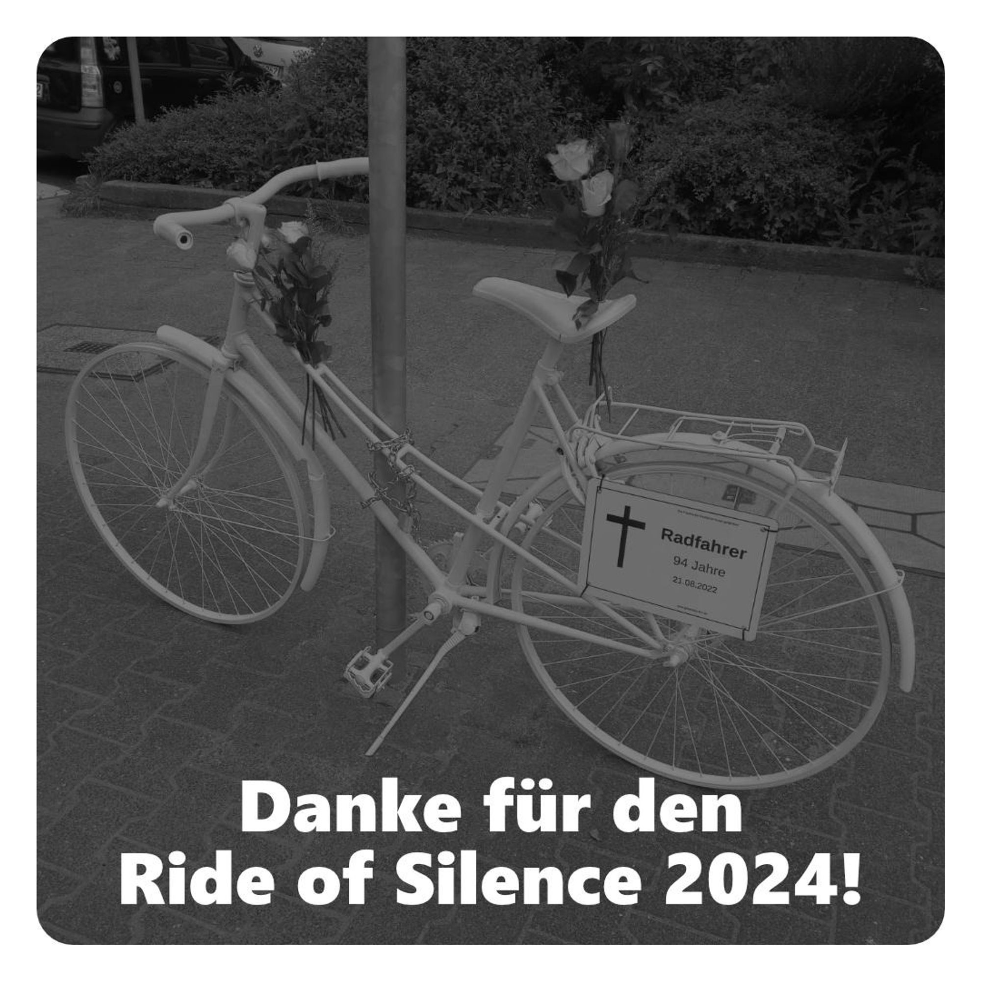 Ein mit Rosen dekoriertes weiß lackiertes Fahrrad ist an einem Mast angekettet. Am Gepäckträger des Fahrrads hängt ein Schild mit der Aufschrift "Radfahrer, 94 Jahre, 21.08. 2022".
Unter dem Foto steht der Text " Danke für den Ride of Silence 2024!"