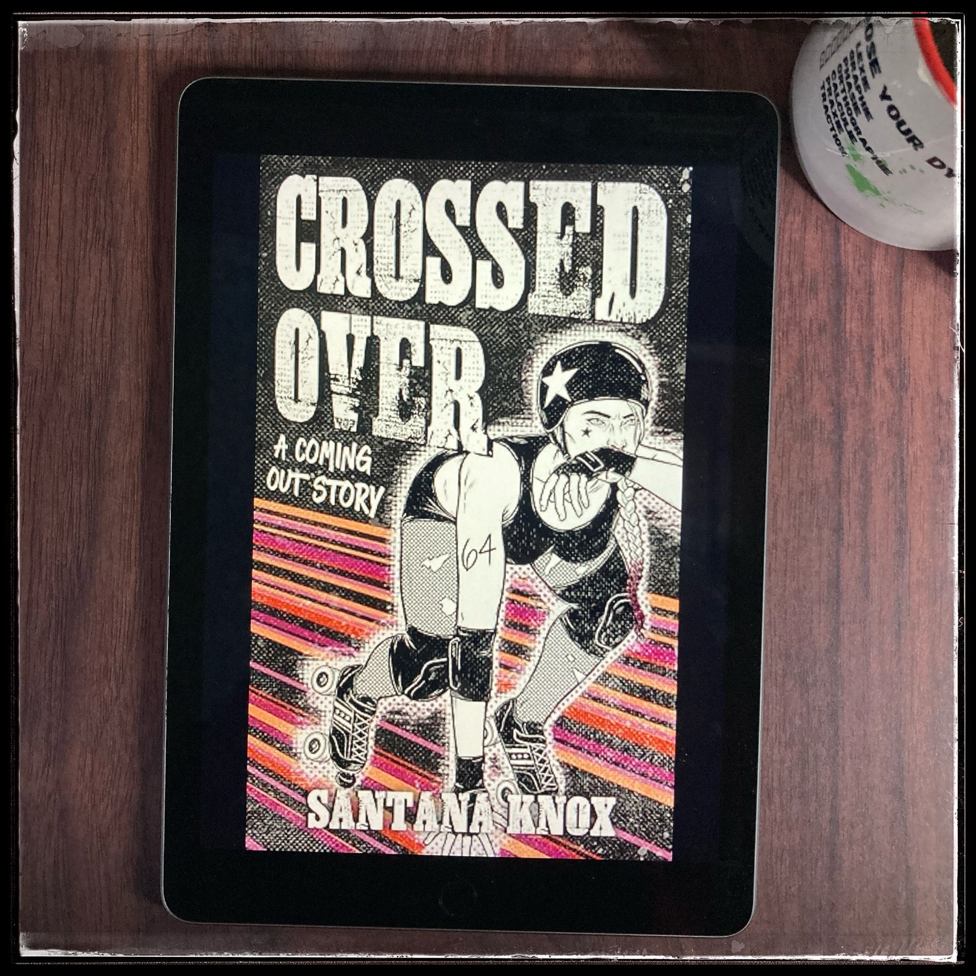 An iPad with the cover of Crossed Over by Santana Knox, next to a mug of tea.