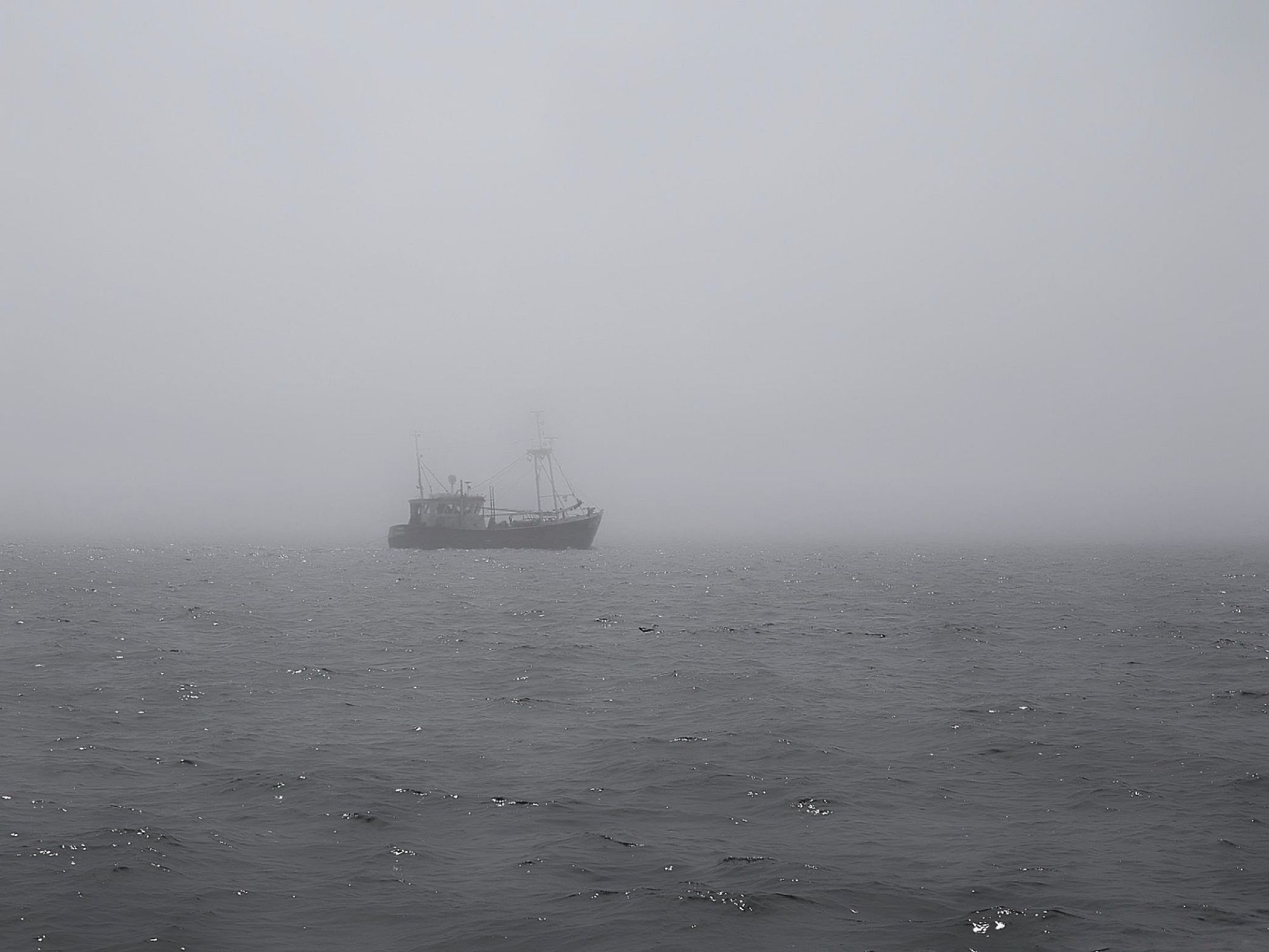 Fishing boat in the fog. Sunlight cascades on the waves