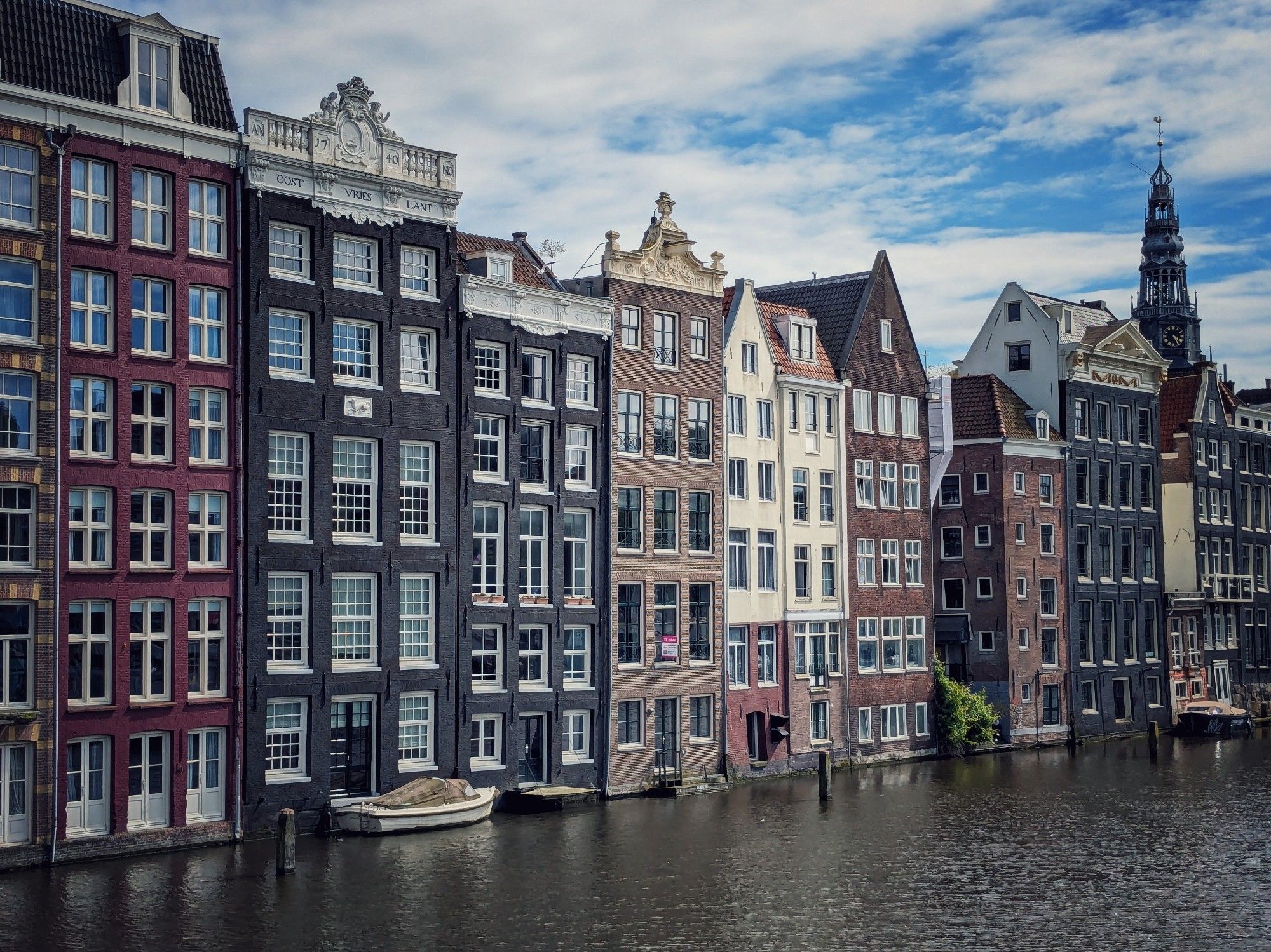 Grachtenpanden in verschillende kleuren langs water bij Rokin.