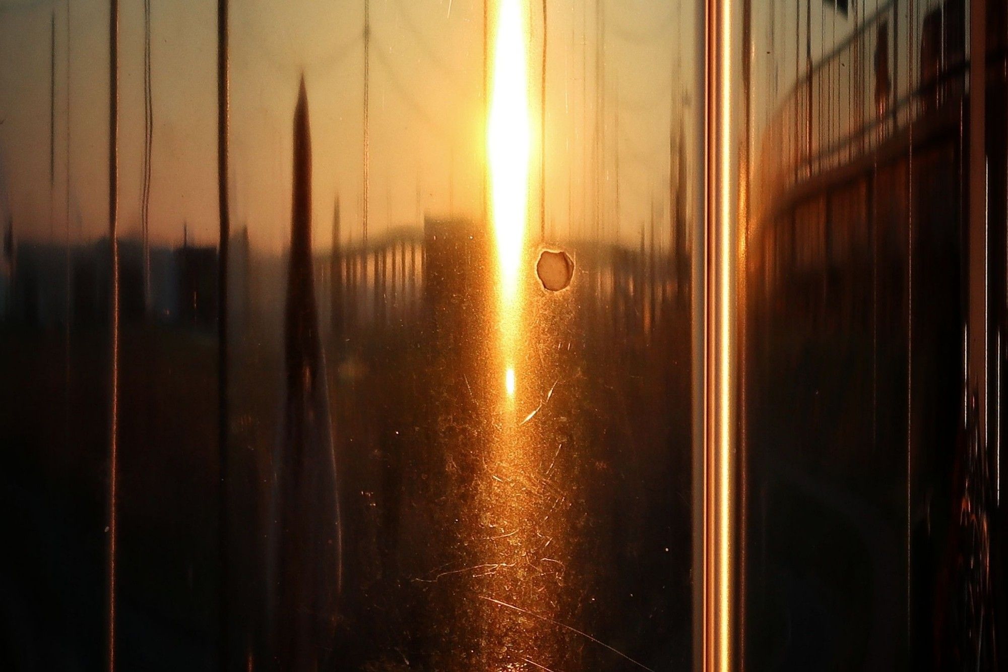 Setting sun in shiny metal pillar.