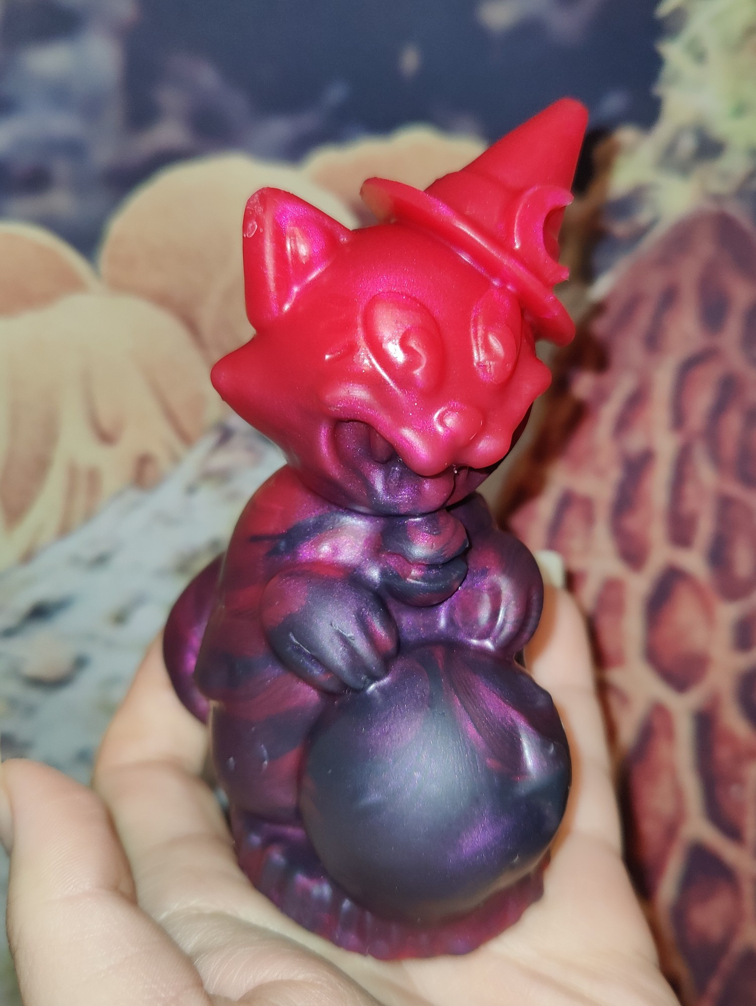 A picture of a magician cat (cat wearing a little witch hat and holding a crystal ball). The cat is from Arkham harbor and is red/purple.