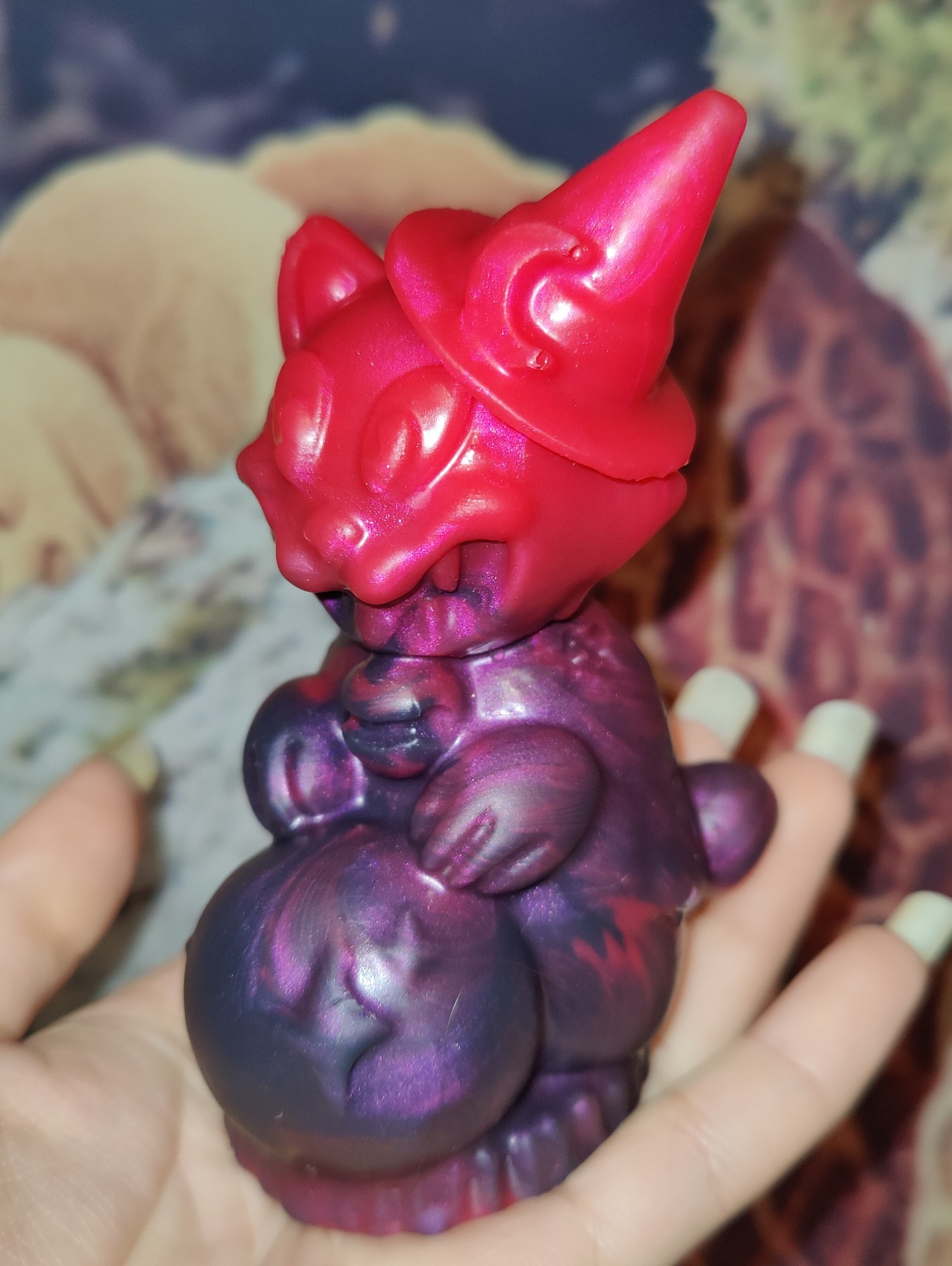 A picture of a magician cat (cat wearing a little witch hat and holding a crystal ball). The cat is from Arkham harbor and is red/purple.