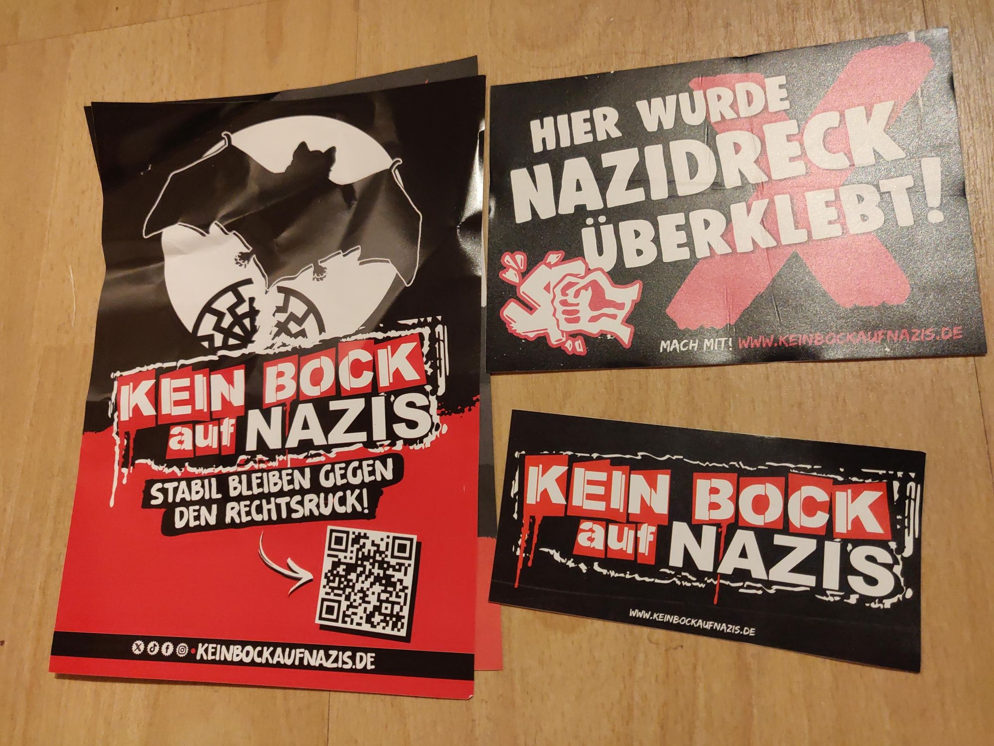 Mehrere Sticker von "Kein Bock auf Nazis" liegen nebeneinander, auf einem steht "Hier wurde Nazidreck überklebt"