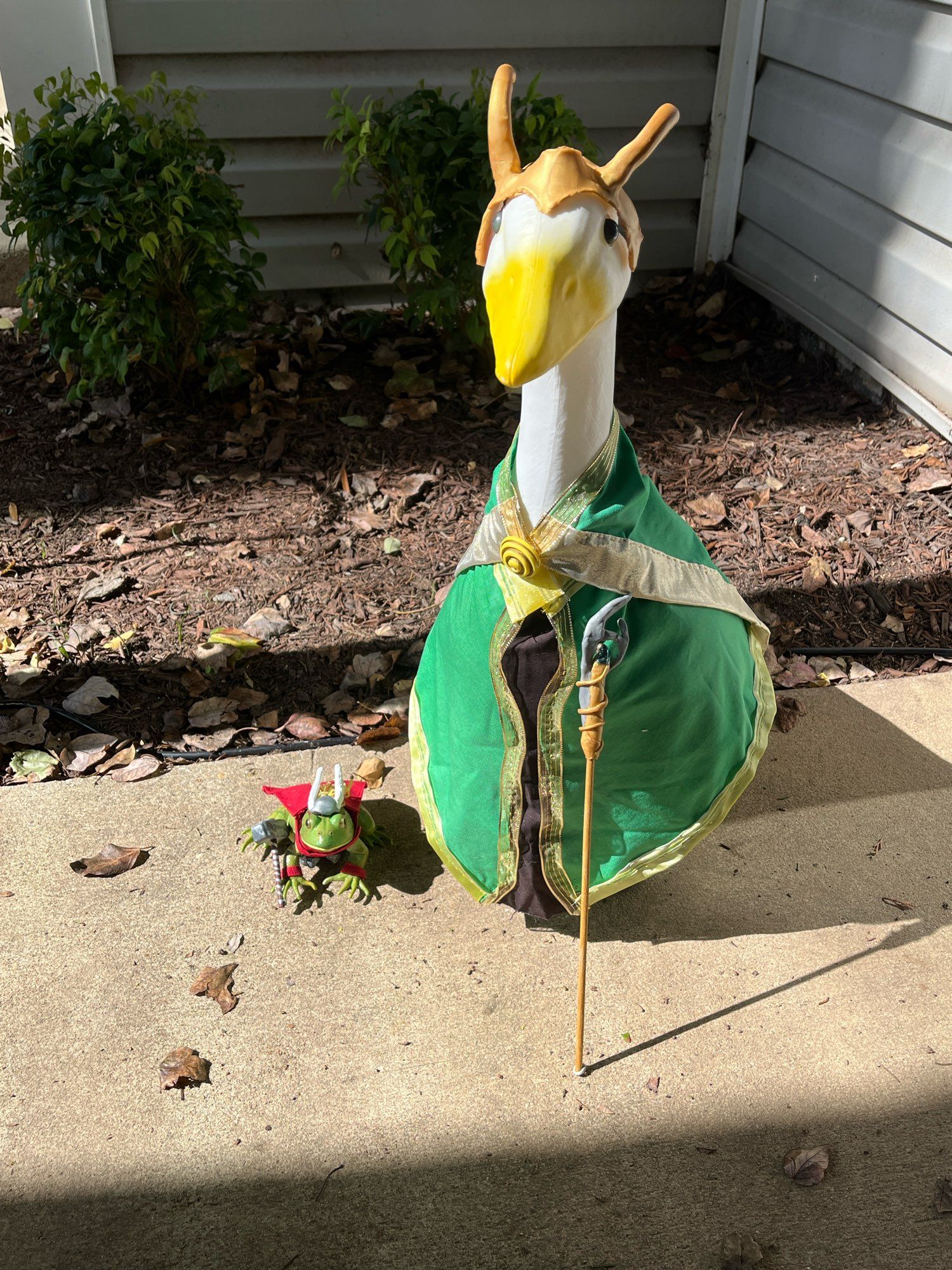 Goose Loki and Throg sit on the patio in front of bushes.