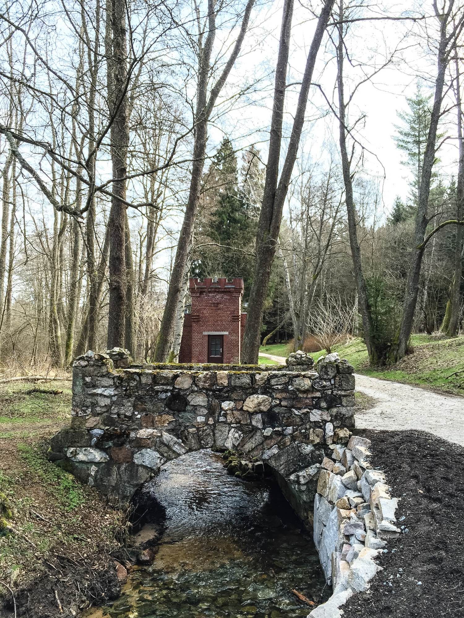 Das Bild zeigt eine ca. 3 m breite alte Steinbrücke über einen Bach im Wald.