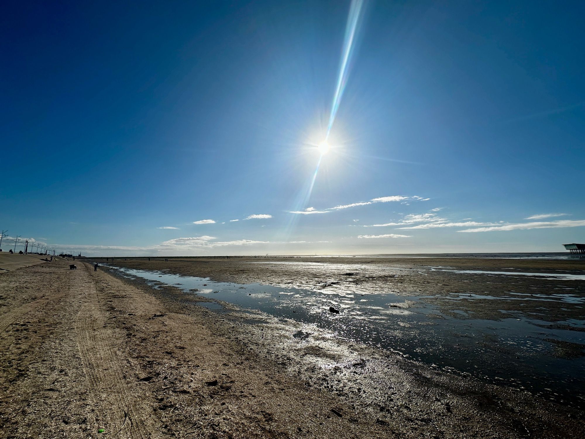 A beach with blue sky and the sun shining.