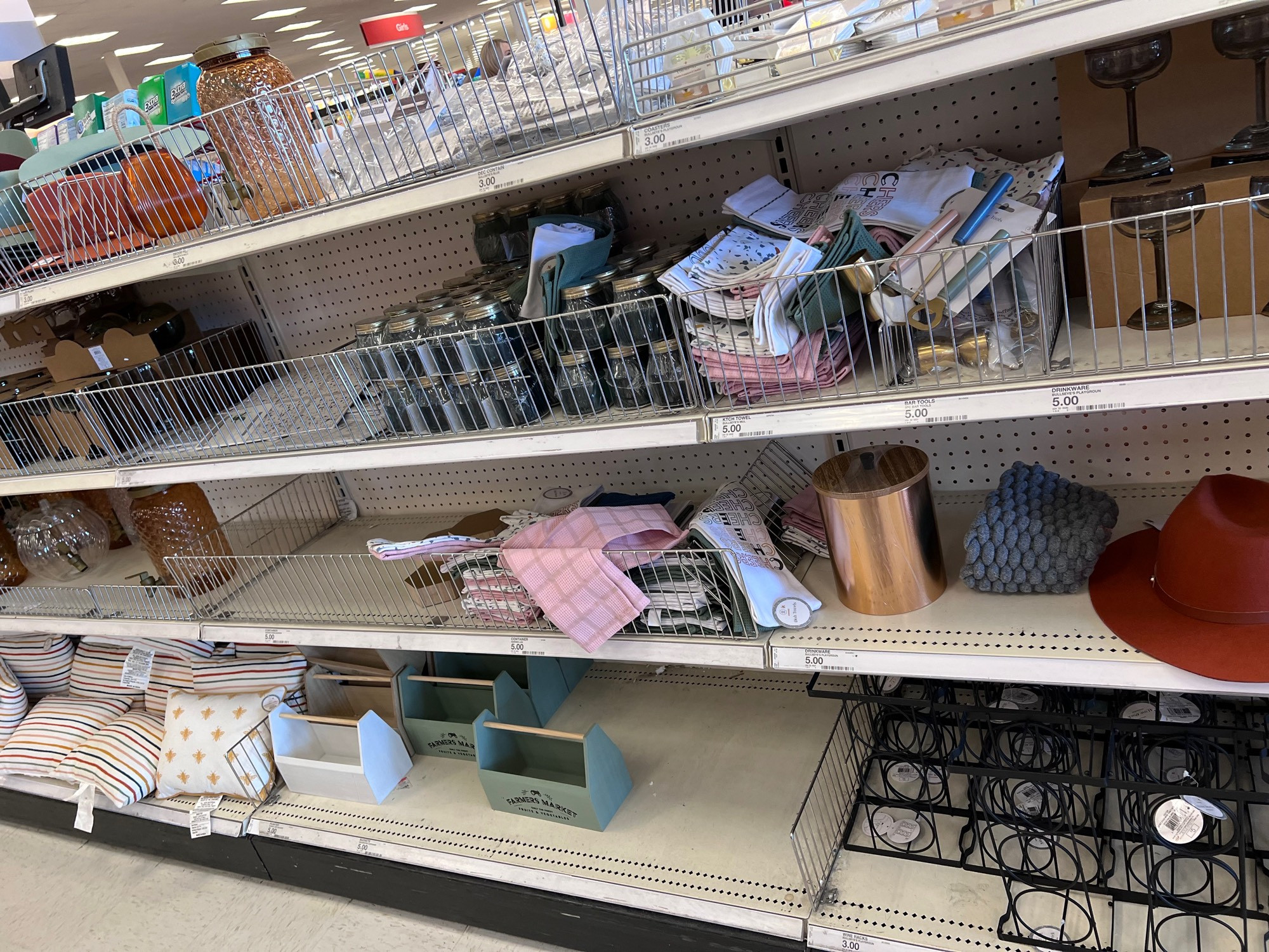 shelf at the target dollar spot. there’s a wine rack, margarita glasses, mason jars, a felt hat, and other white lady knick knacks 