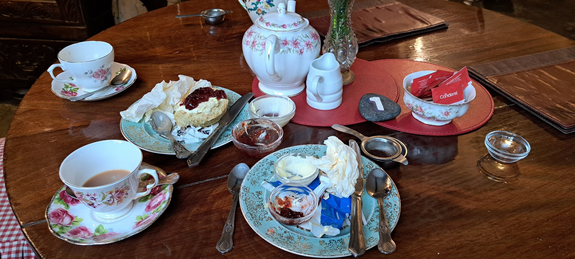 Cornish cream tea with traditional tea pot, cups & saucers. Nearly finished.