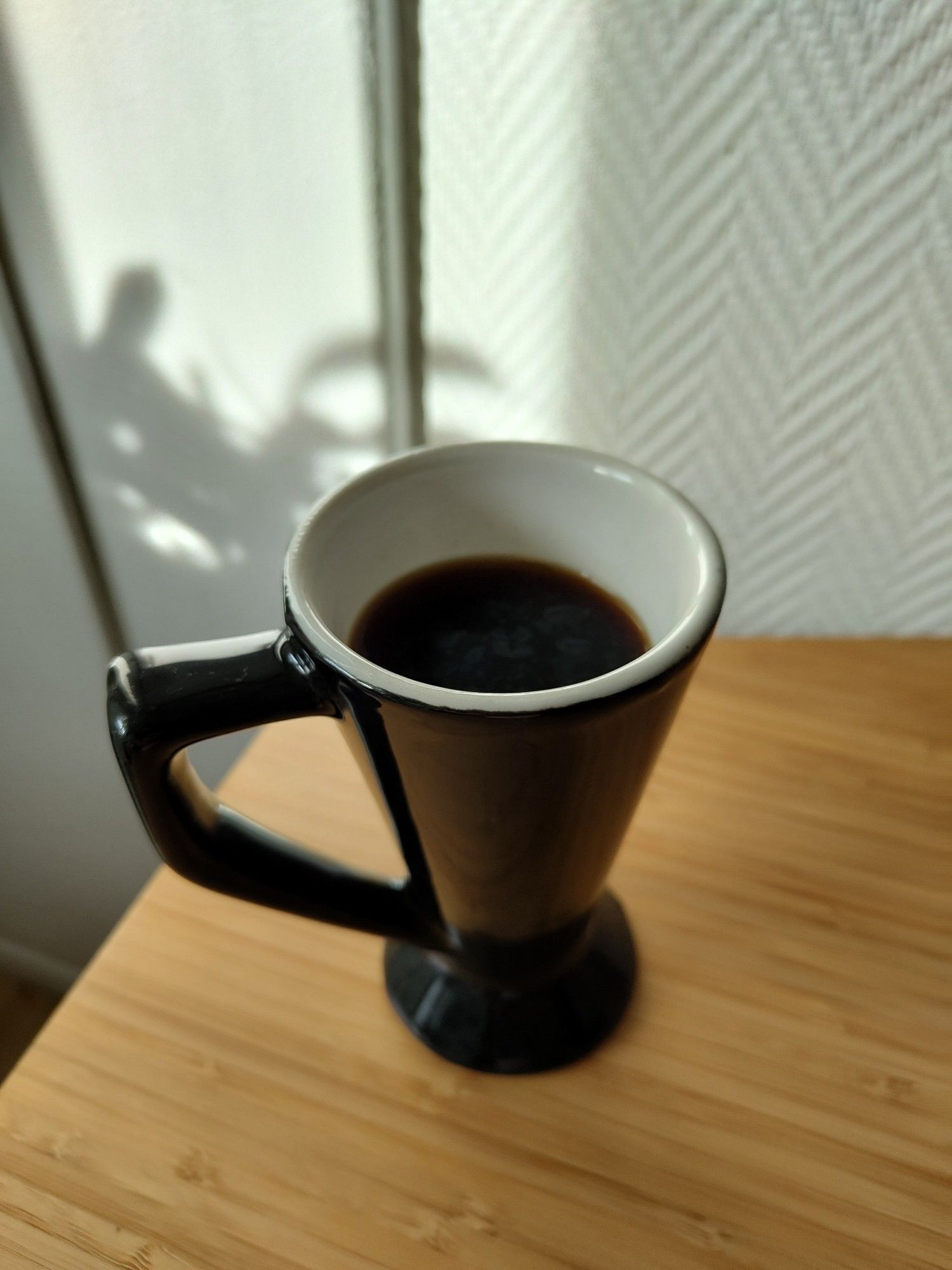 A cup of coffee in a black mug on a wooden table.