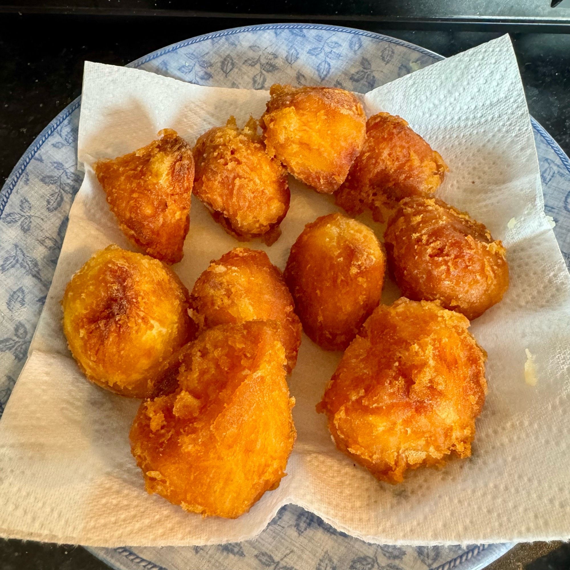 A plate of freshly made golden-brown roast potatoes, arranged on a paper towel, showing a crispy exterior and a soft interior.