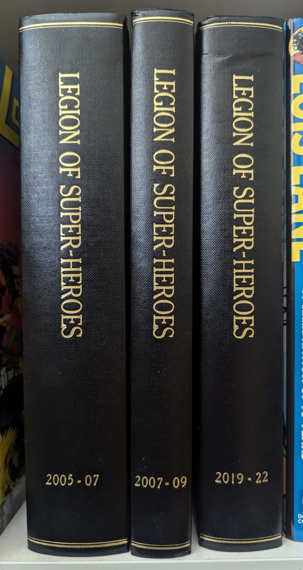 Three books, black with gold lettering. All of them are titled "Legion of Super-Heroes." The first (and thickest) is labeled "2005-07," the second (and slimmest) is labeled "2007-09," and the third is labeled "2019-22."