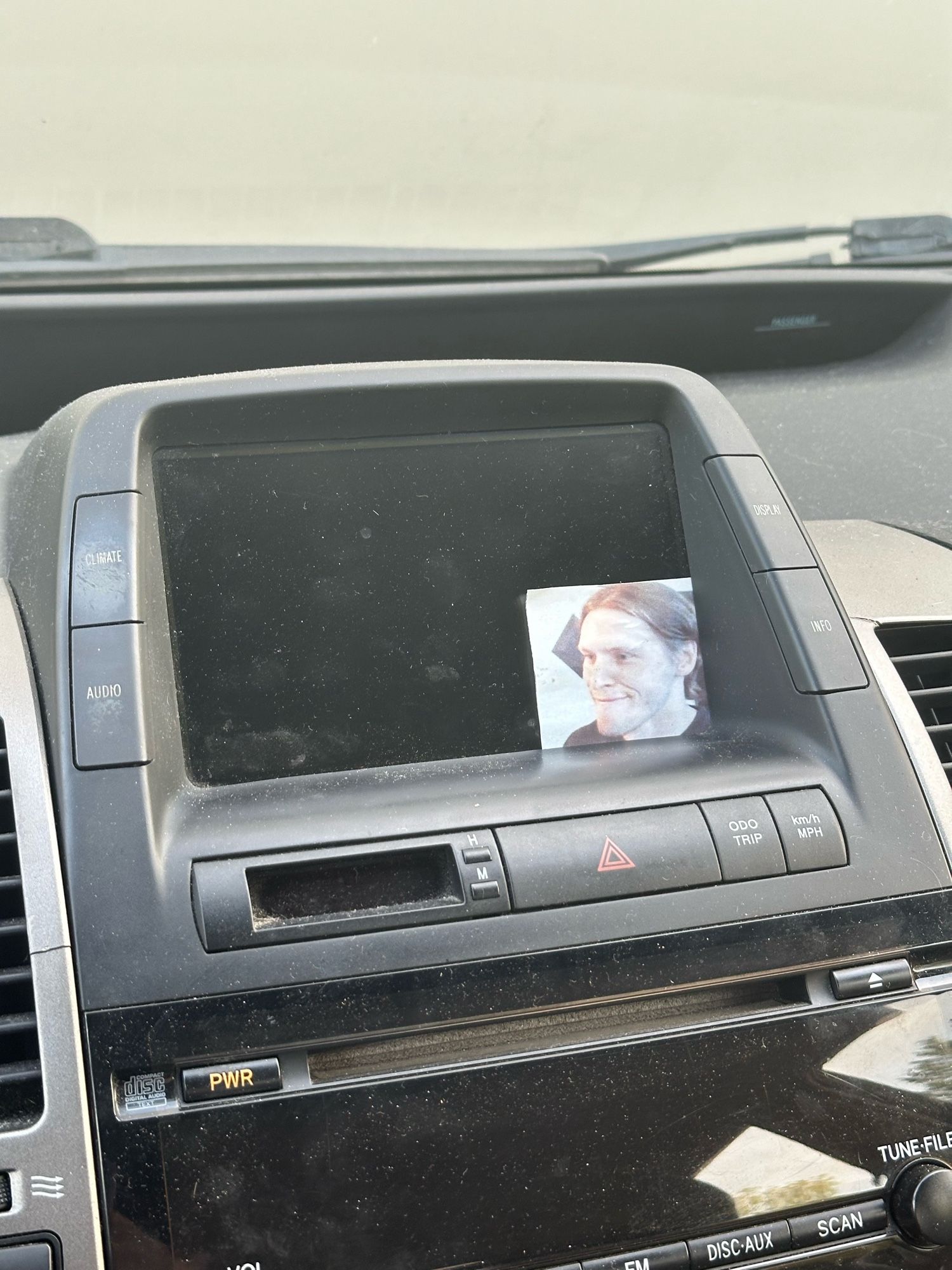 Photo of my car’s dashboard. A printed out picture of jerma is stuck in the bottom right corner of the screen so it looks like he’s streaming