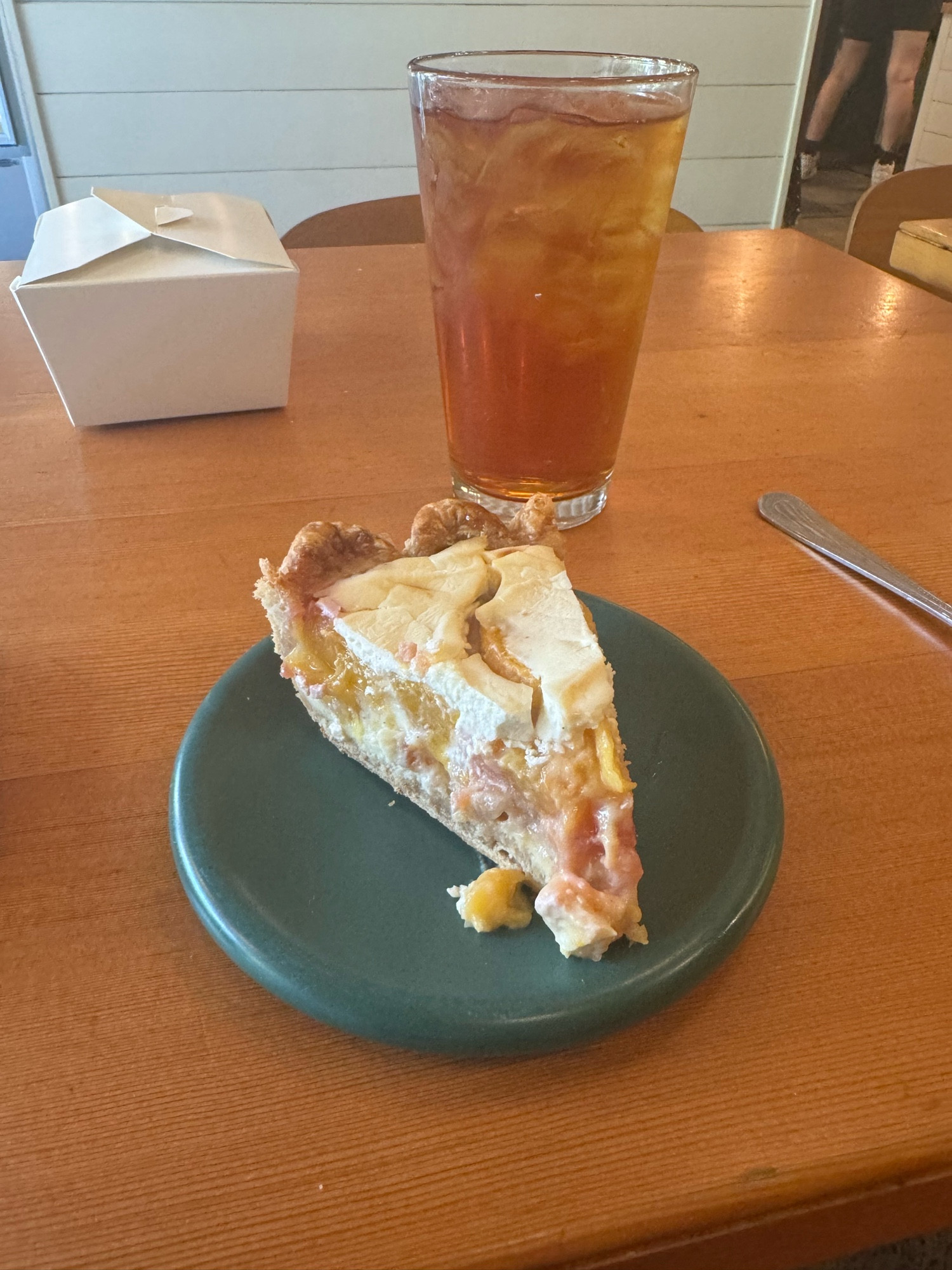 Piece of sour cream peach pie and a glass of iced tea