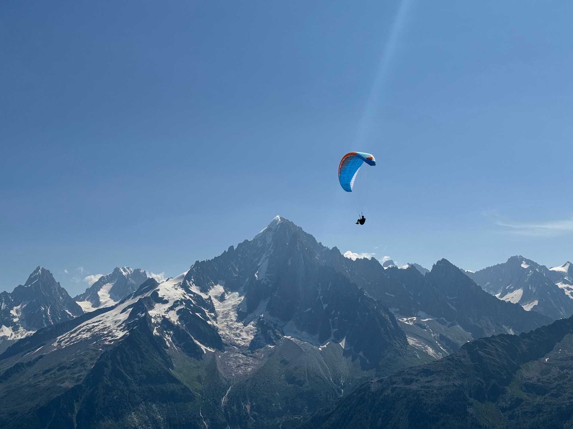 A paraglider passing one of the peaks of the Mt Blanc massif