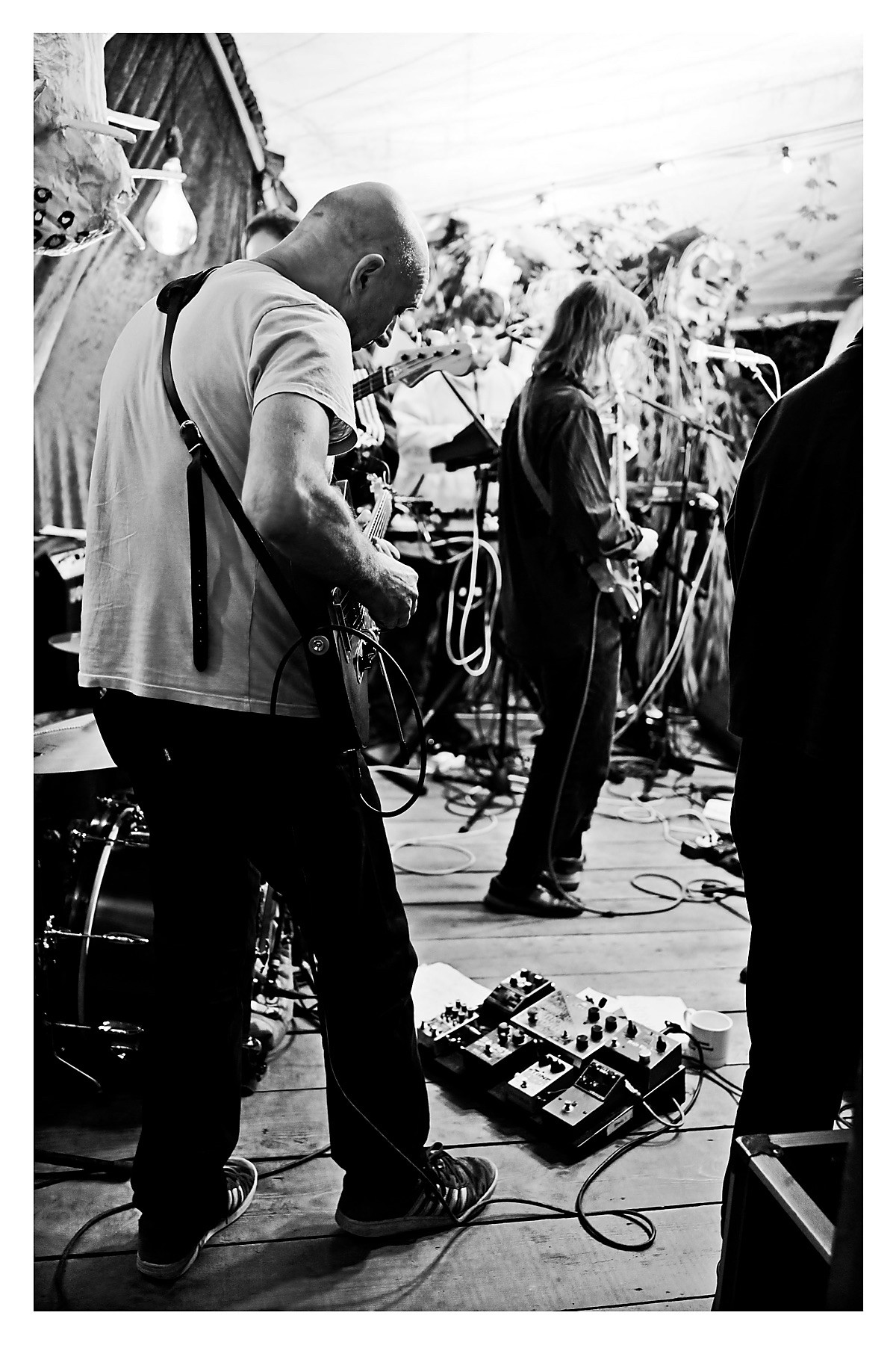 From left of stage, behind Neil on guitar, he’s looking down towards his pedal board. Ahead of him Rozi front of stage.