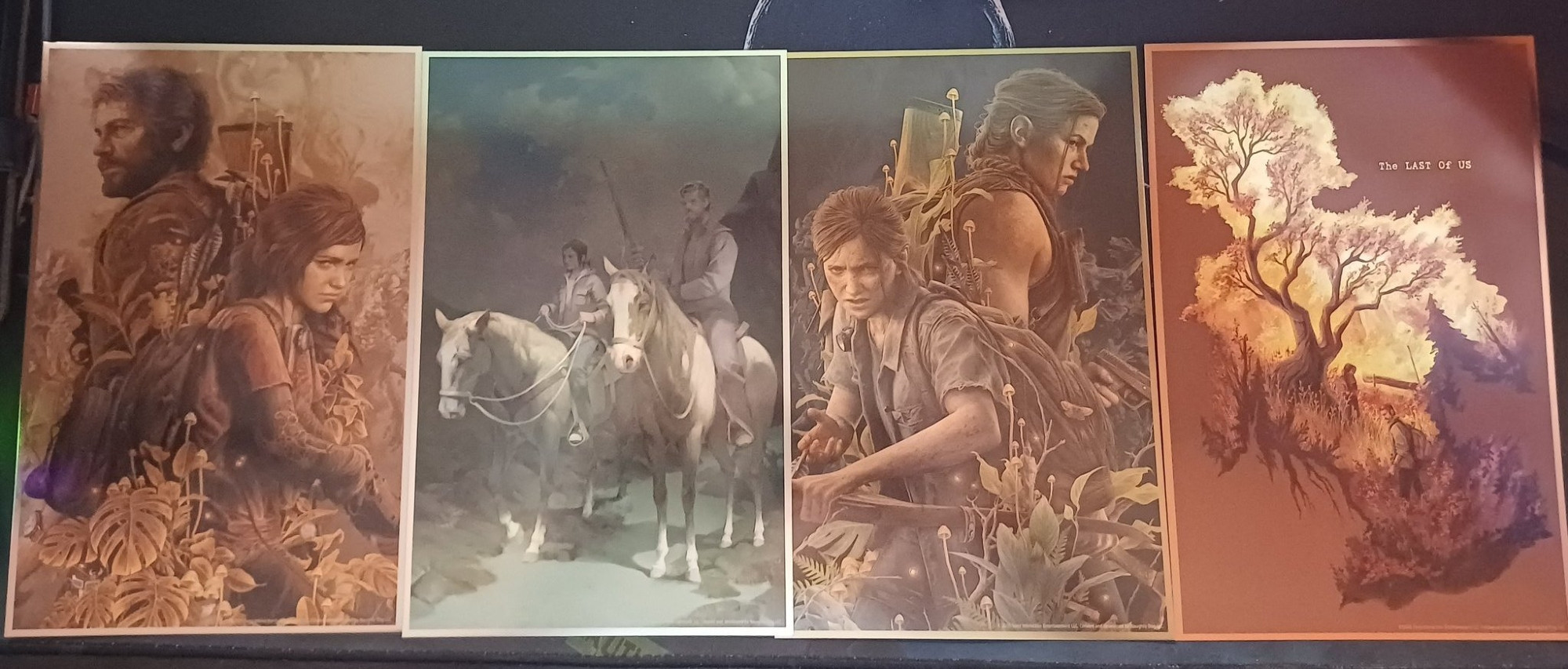 Four art prints side by side: Ellie and Joel, Ellie and Joel on horseback, Ellie and Abby, and the environment in a clicker silhouette