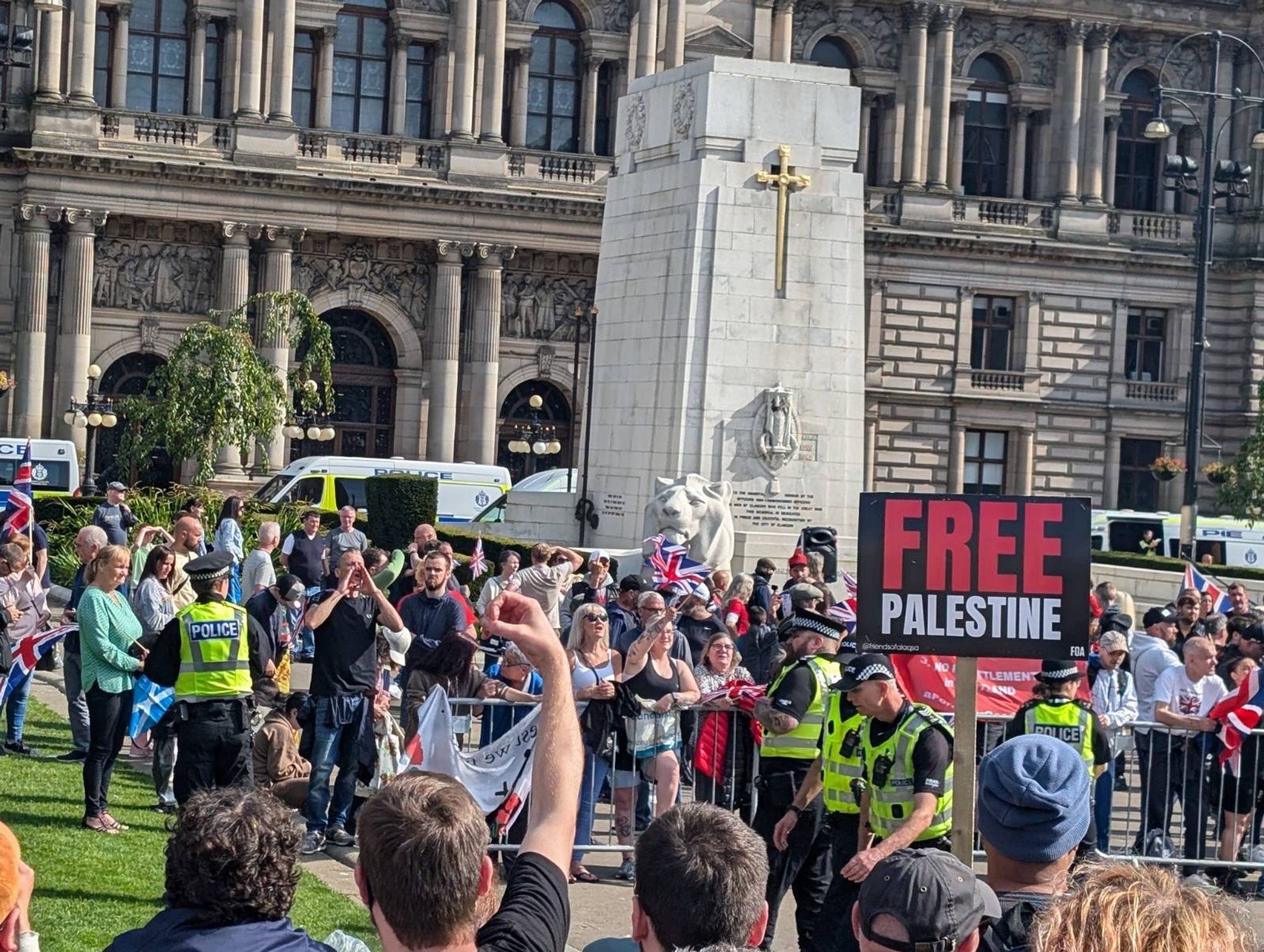 Anti fash protestor holds up a wanker sign at a small group of far right protestors and the police protecting them