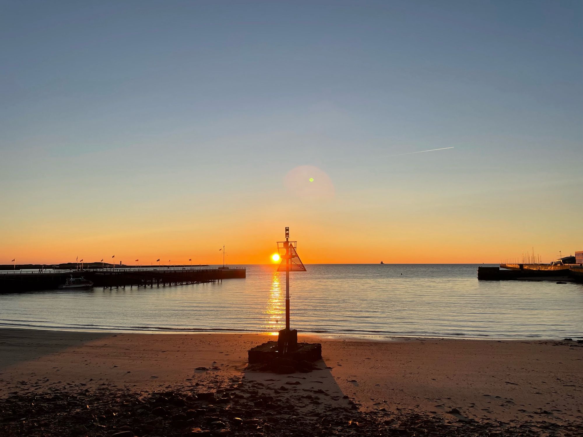 Sonnenaufgang über dem Meer hinter einem Seezeichen