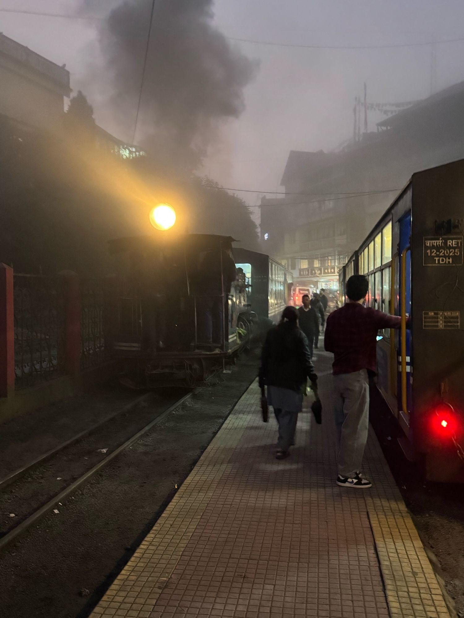 The glaring light of a steam train in fog and smoke.