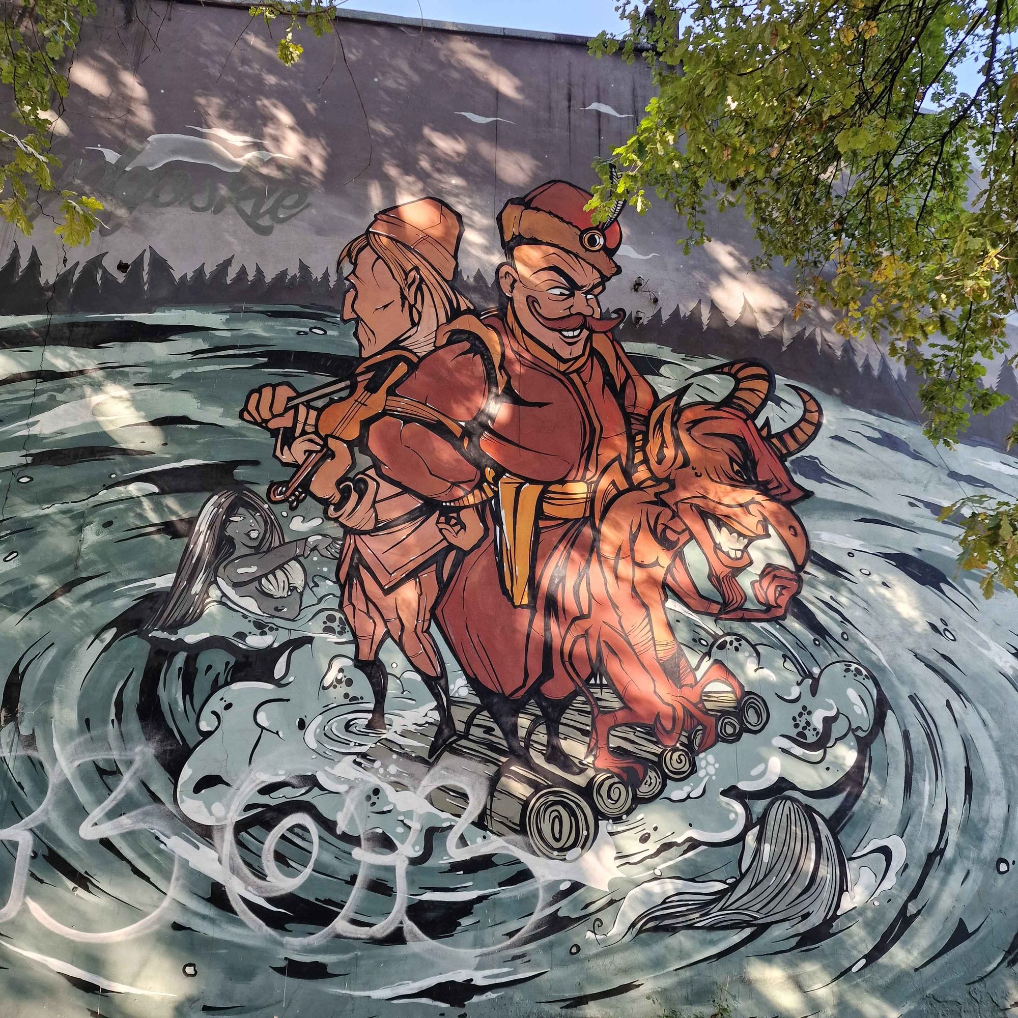 Streetart: zwei Figuren auf einem kleinen Holzfloß, ein dünner Geiger und ein dickerer Mann mit Teufel, um das Floß ist Wasser als Strudel dargestellt, in dem Meerjungfrauen schwimmen