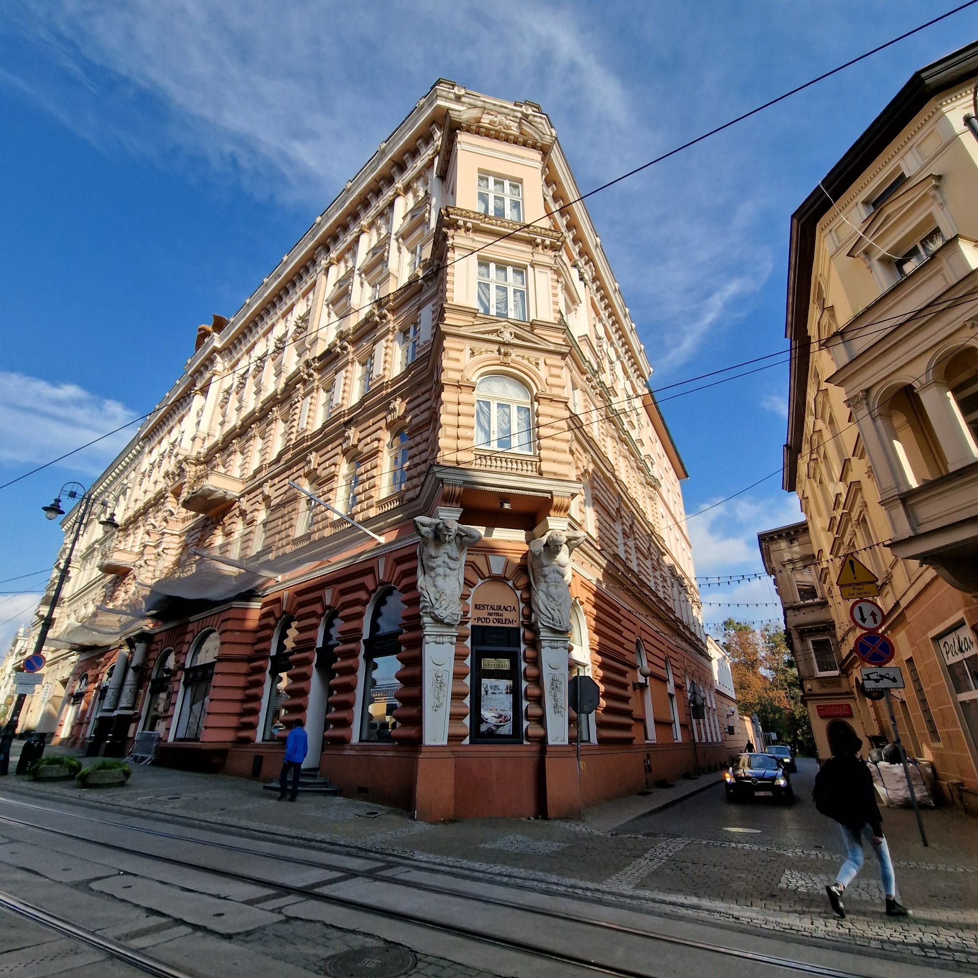 Alter Gebäude um 1900 im Sonnenlicht, davor Straßenbahnschienen