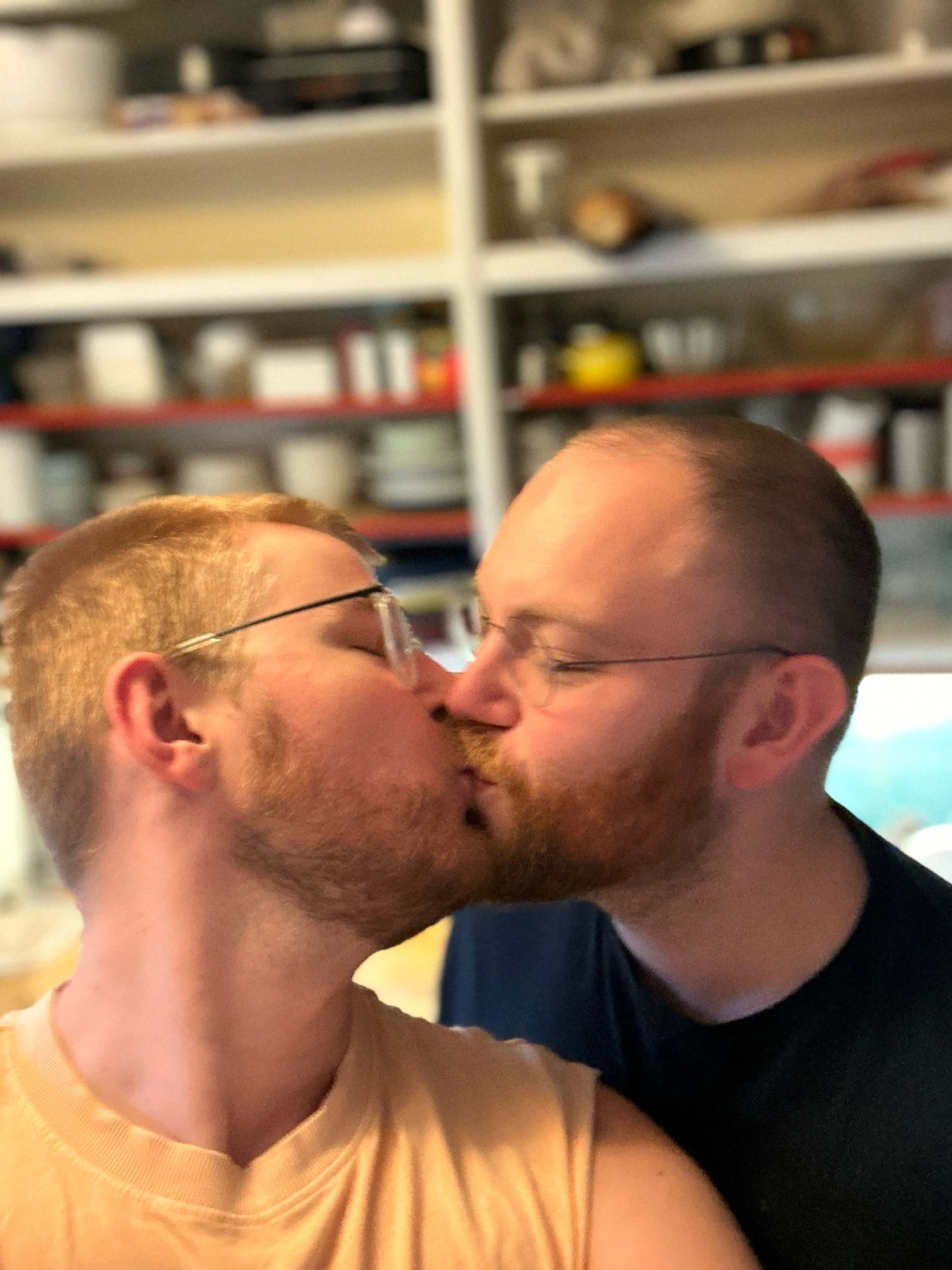 Two guys with glasses kissing